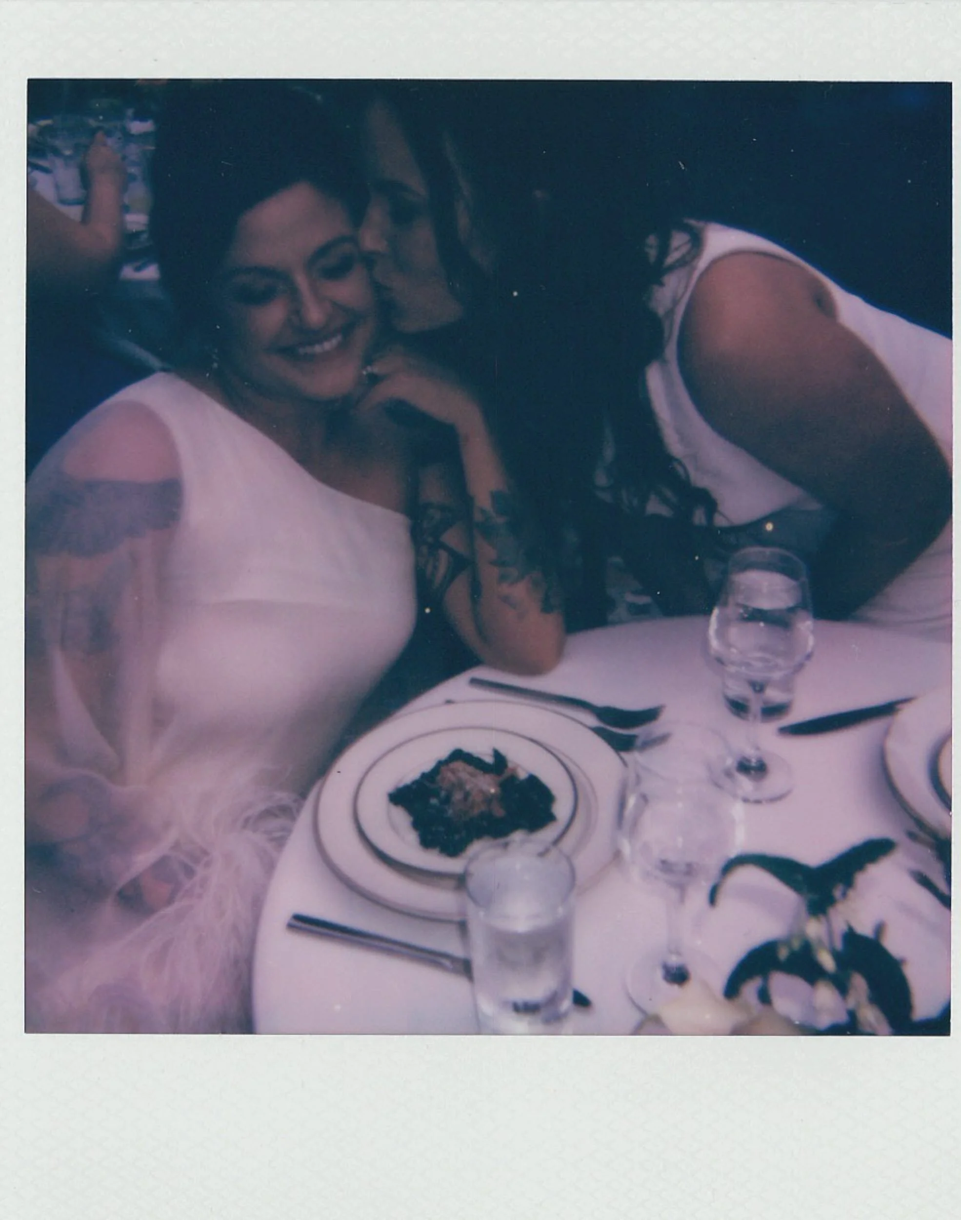 A polaroid of a newlywed leaning over and kissing their partner's cheek