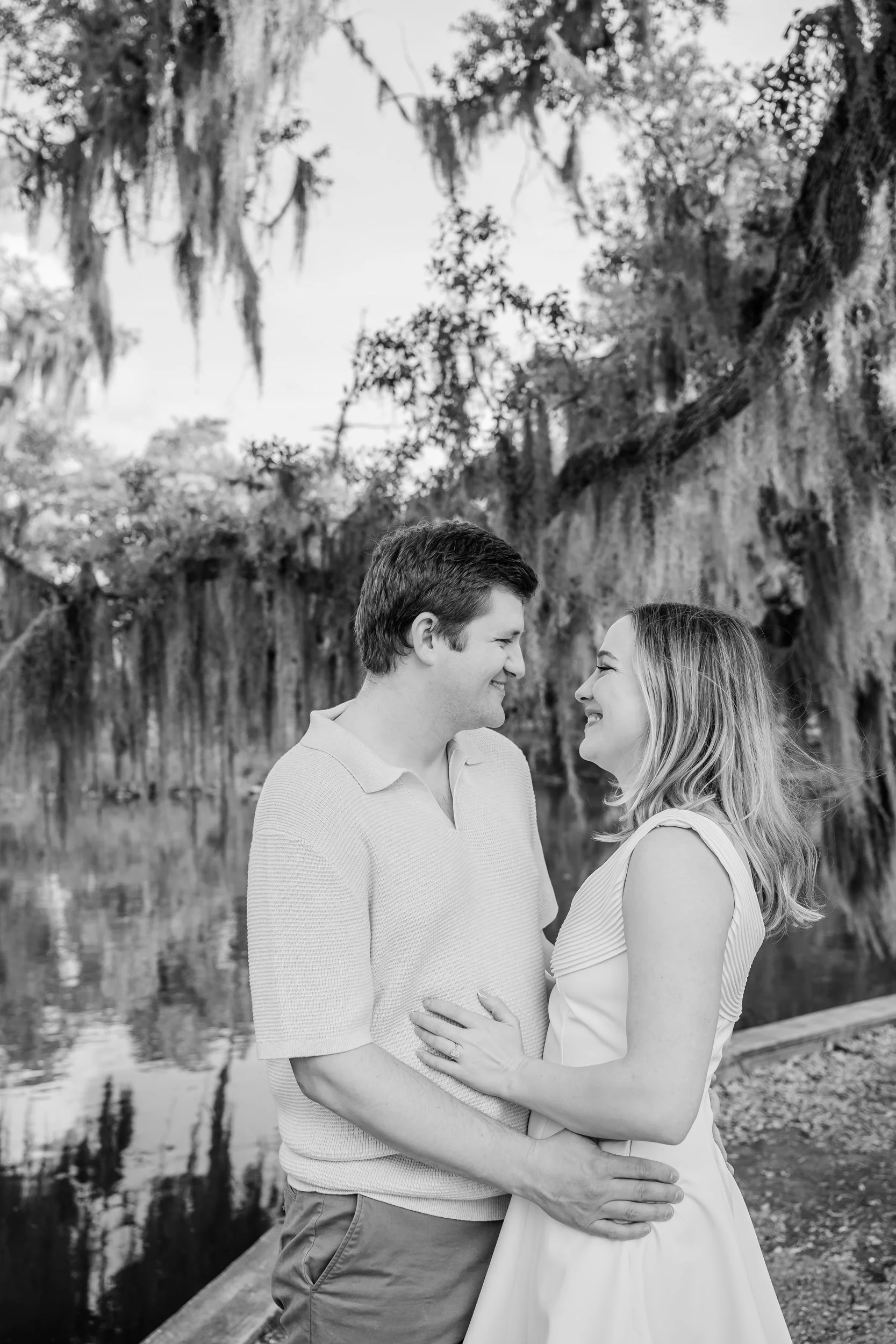 A couple with their arms around each other as they smile at each other