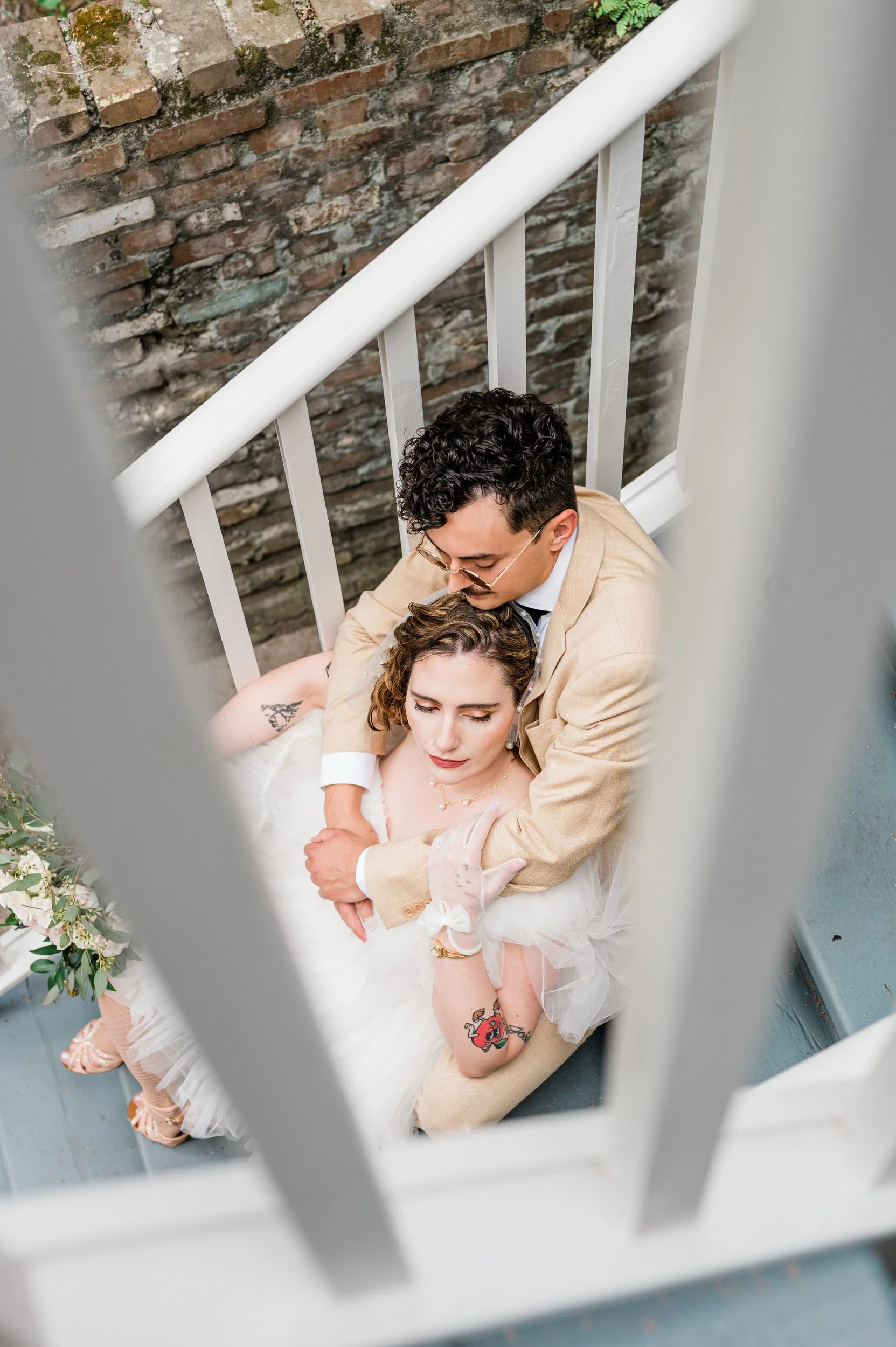 A newlywed couple sitting on a staircase as one leans back into the other