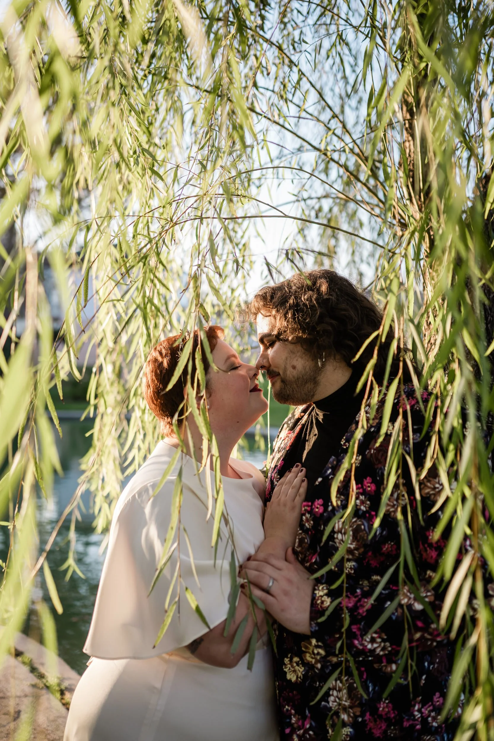 Newlyweds leaning in to kiss with tree branches flowing in front of them