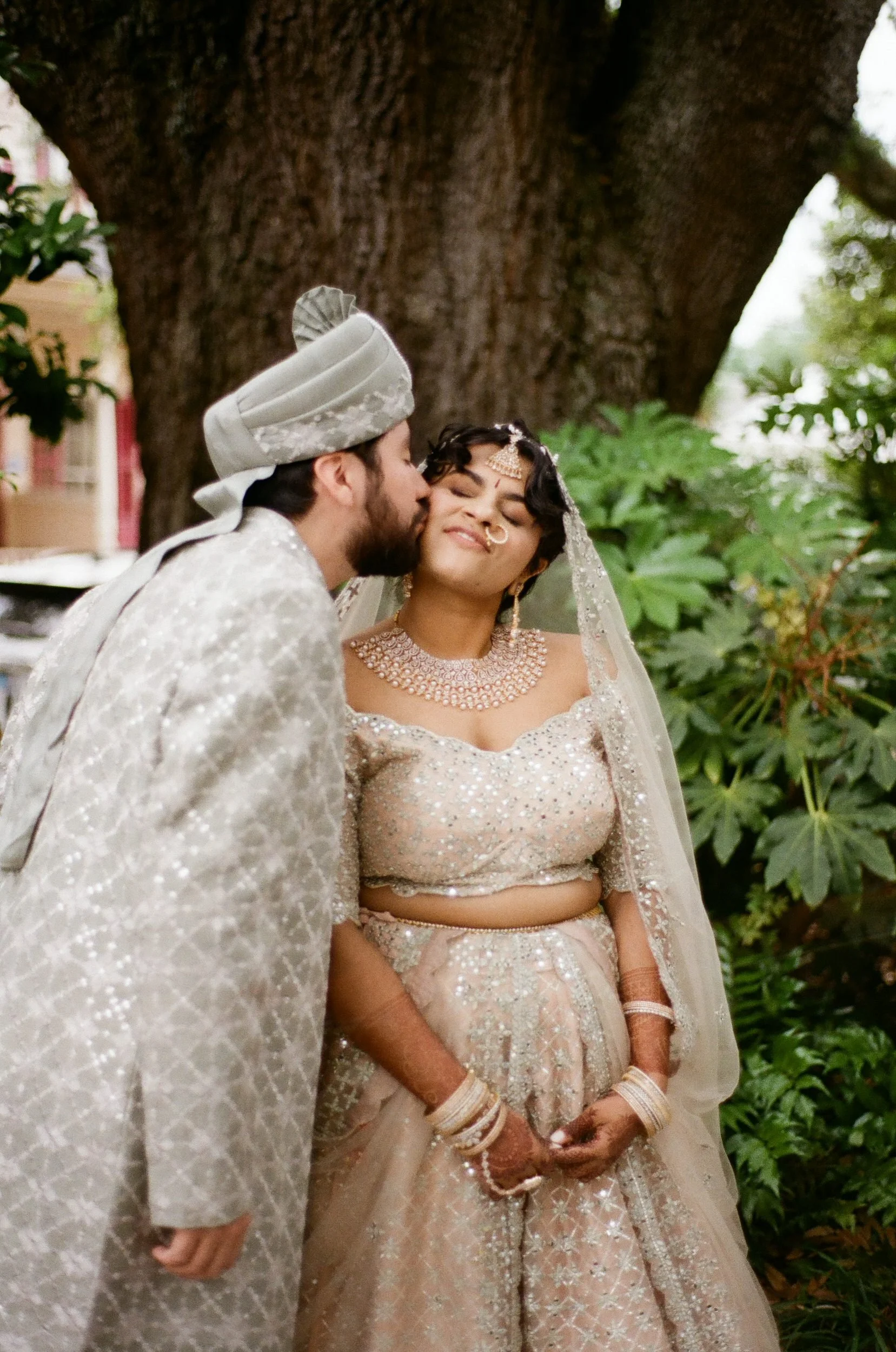 A newlywed kissing their partner's cheek as they smile