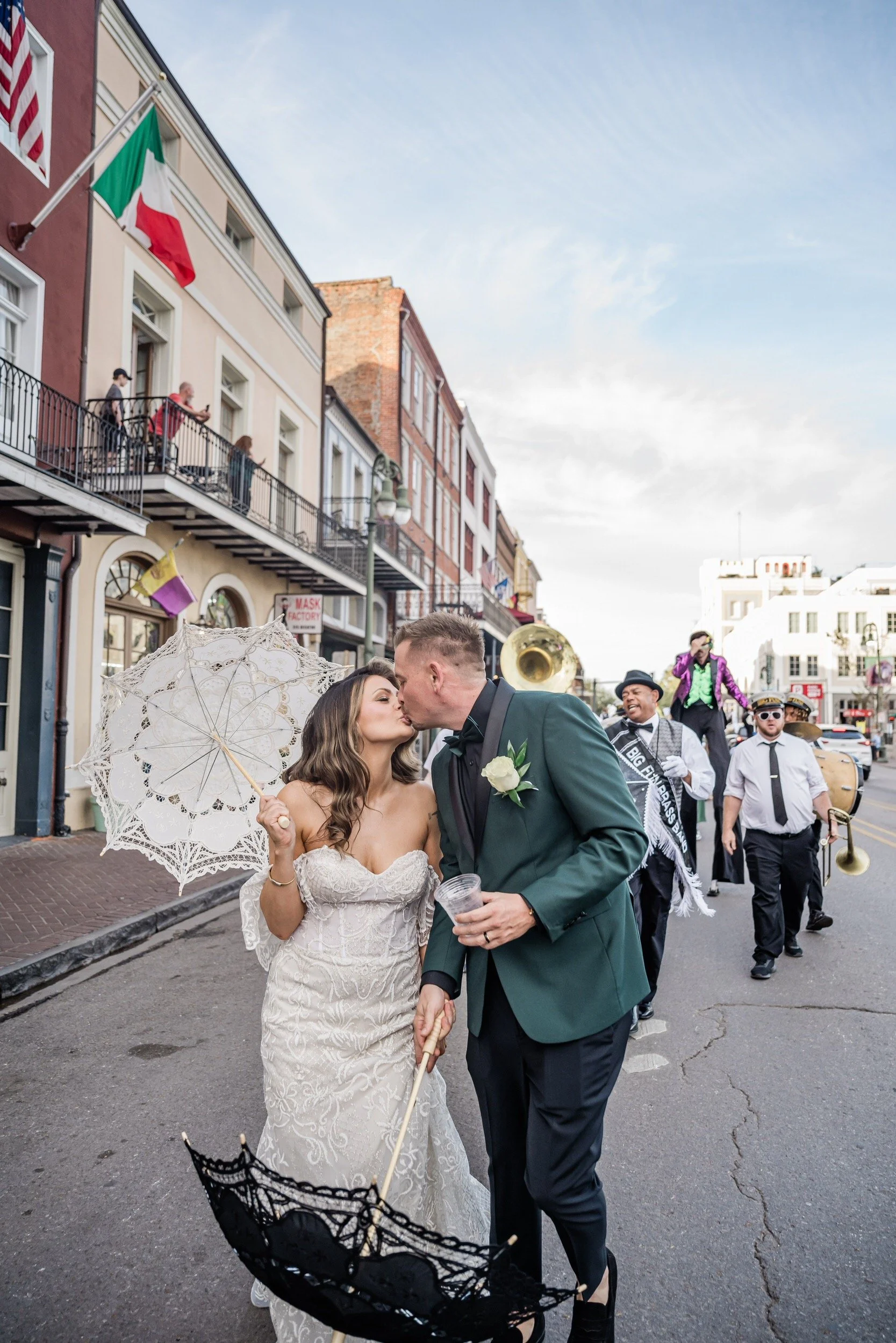 A newlywed couple kissing during their second line parade in New Orleans