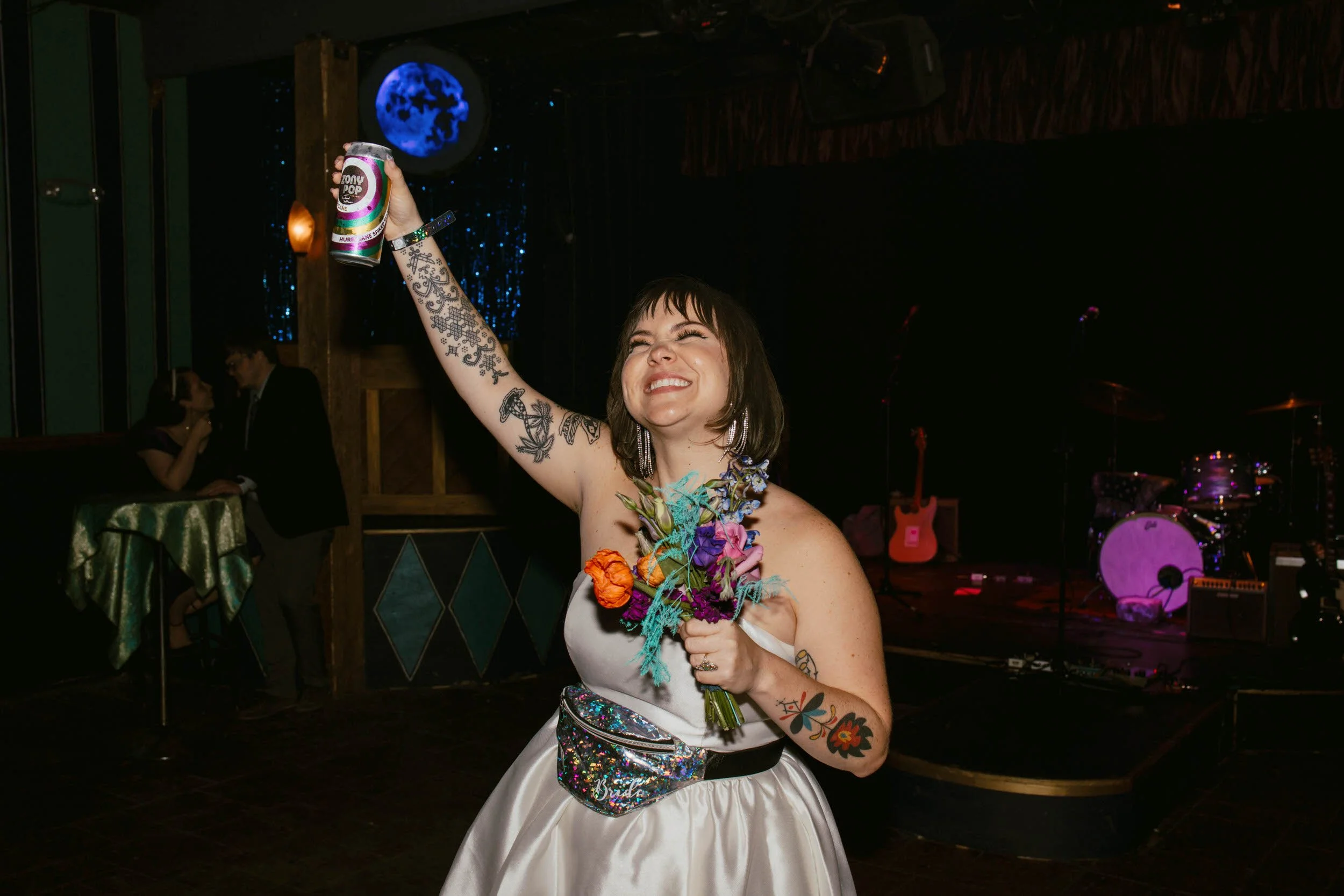 Ash celebrating while holding a bouquet in one hand and a tall can in the other