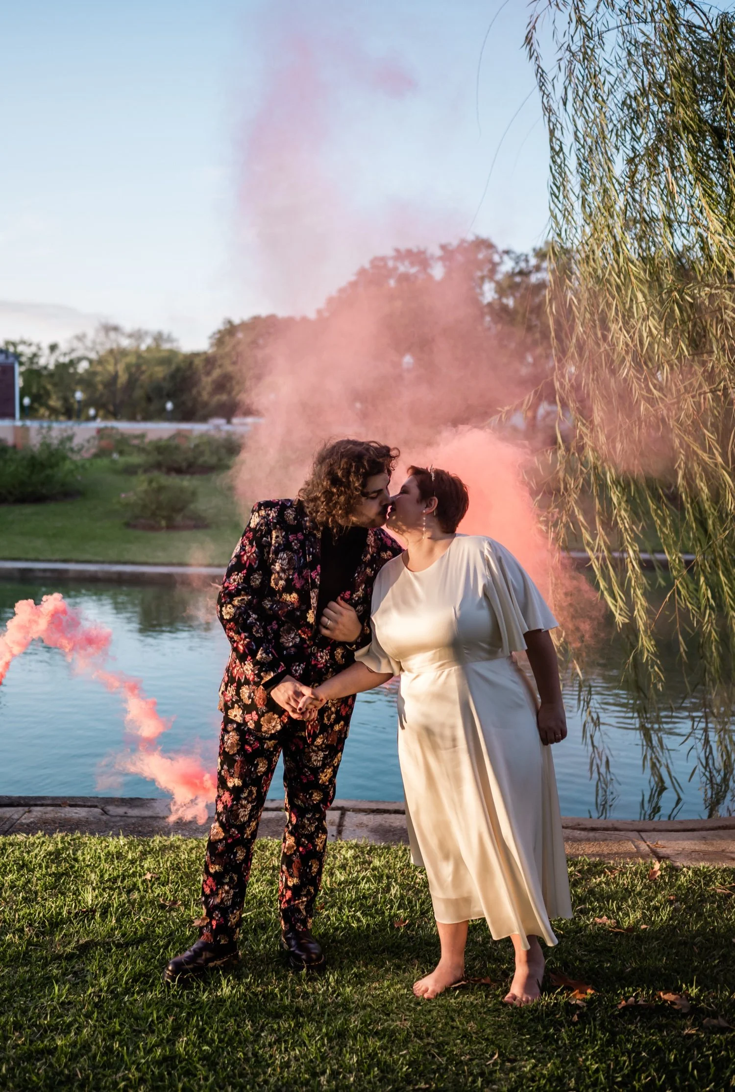 Newlyweds kissing with pink smoke behind them