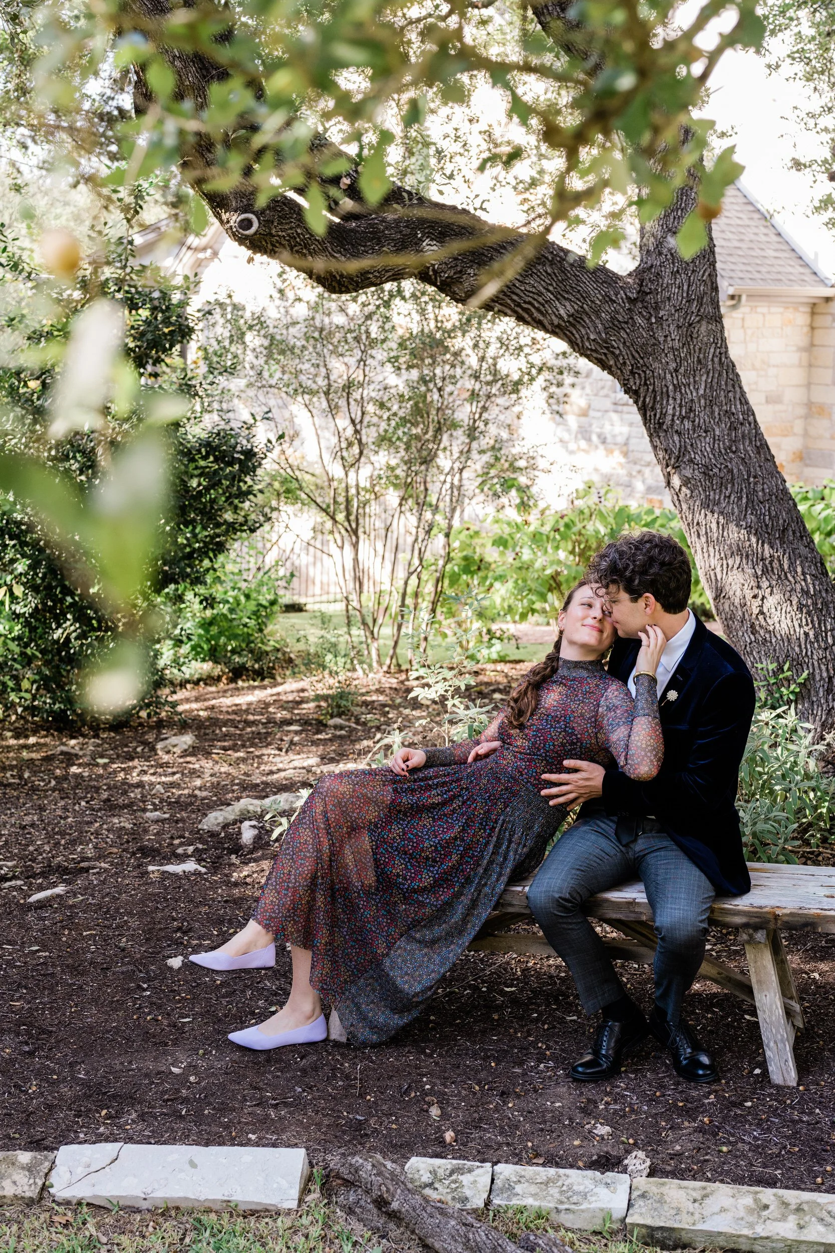 A couple sitting on a bench together as one leans back into the other