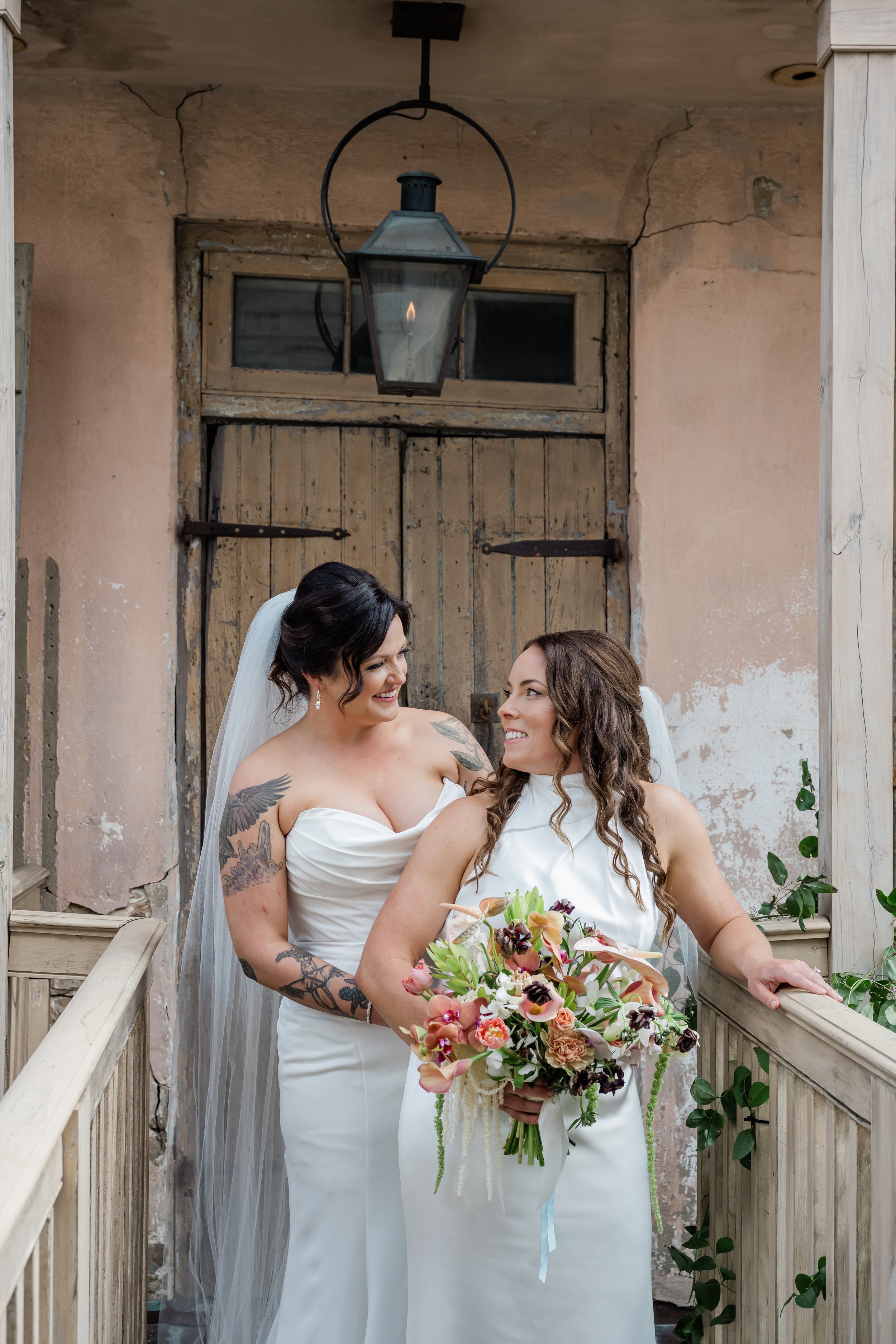 A newlywed standing behind their partner with their hands on their waist as they smile at each other