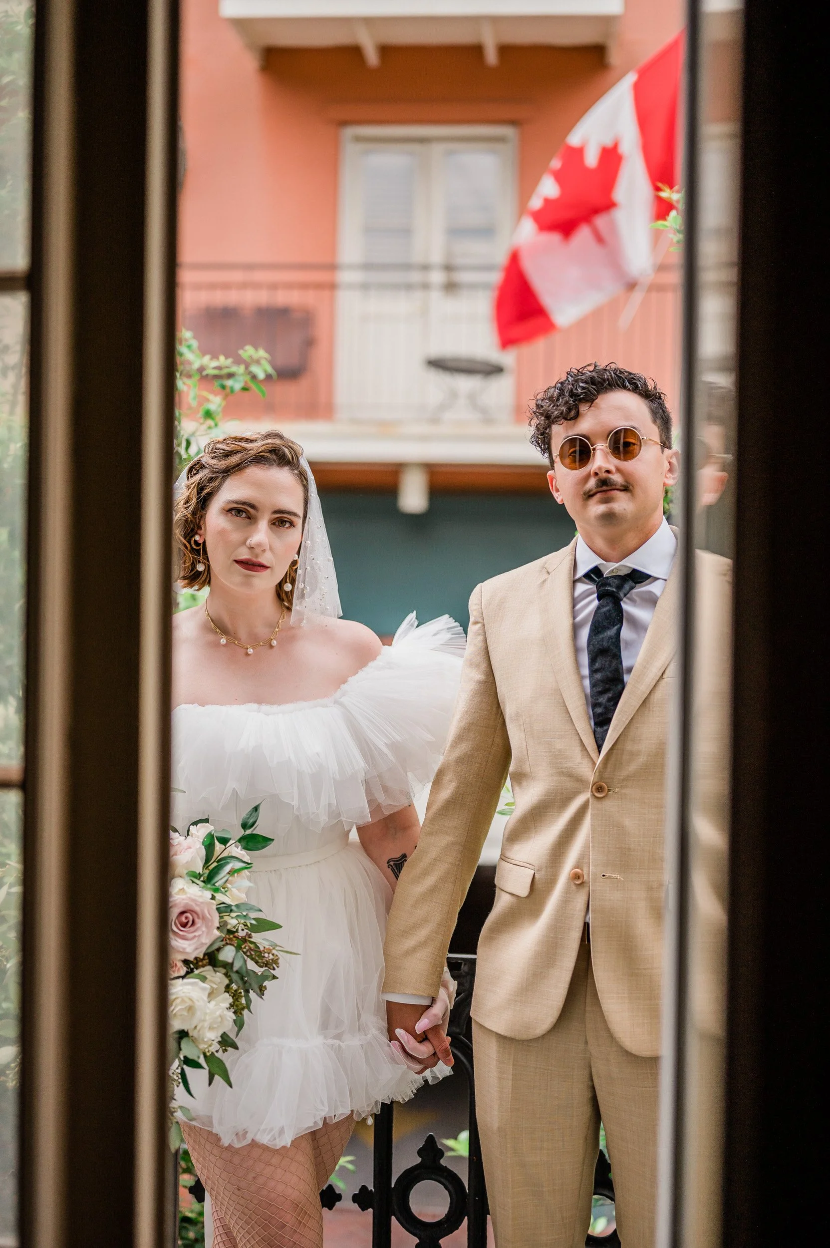Newlyweds holding hands and looking through a small window