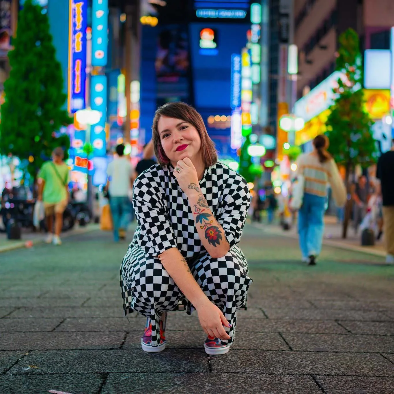 Ash squatting down and smiling on a city sidewalk