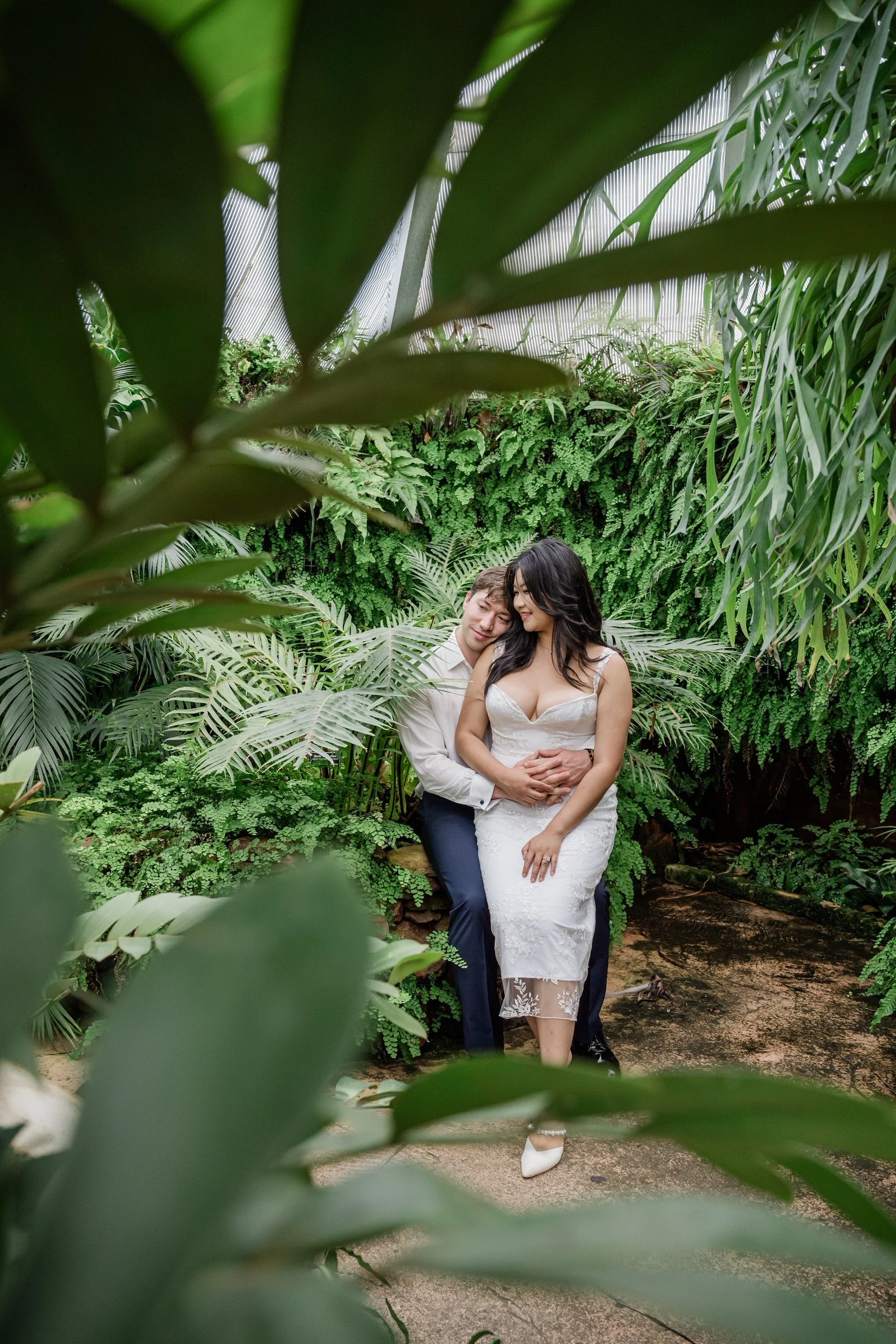A person sitting on a bench with their arms around their partner's waist in front of them