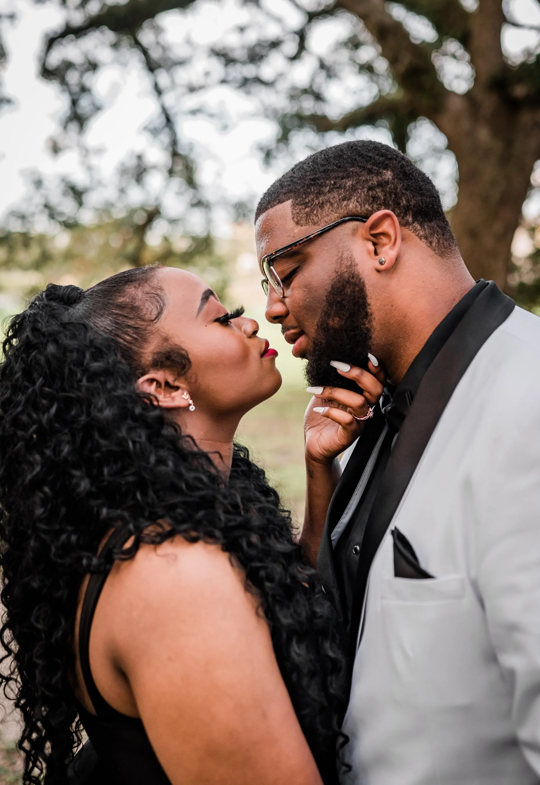 Newlyweds leaning in to kiss while one holds the other's chin