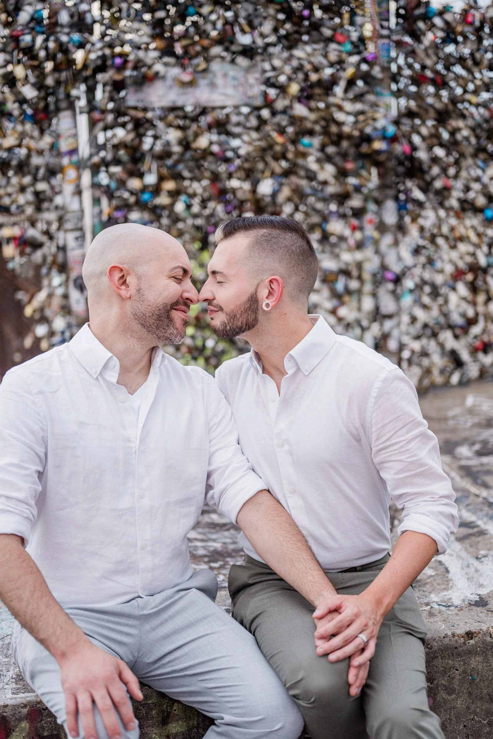 A couple sitting together as one rests their hand on the other's knees while leaning in to kiss