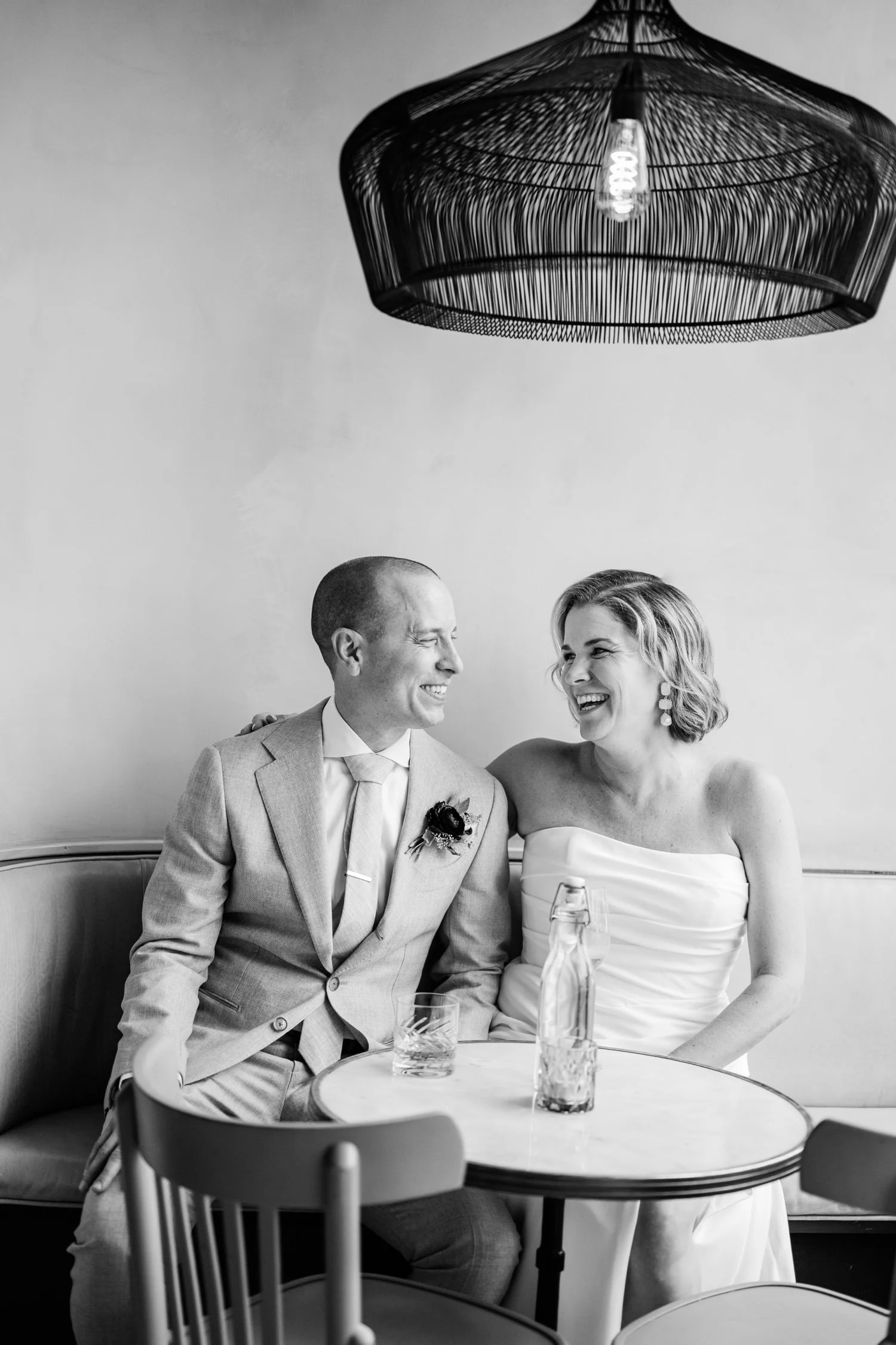 Newlyweds sitting at a small table together laughing