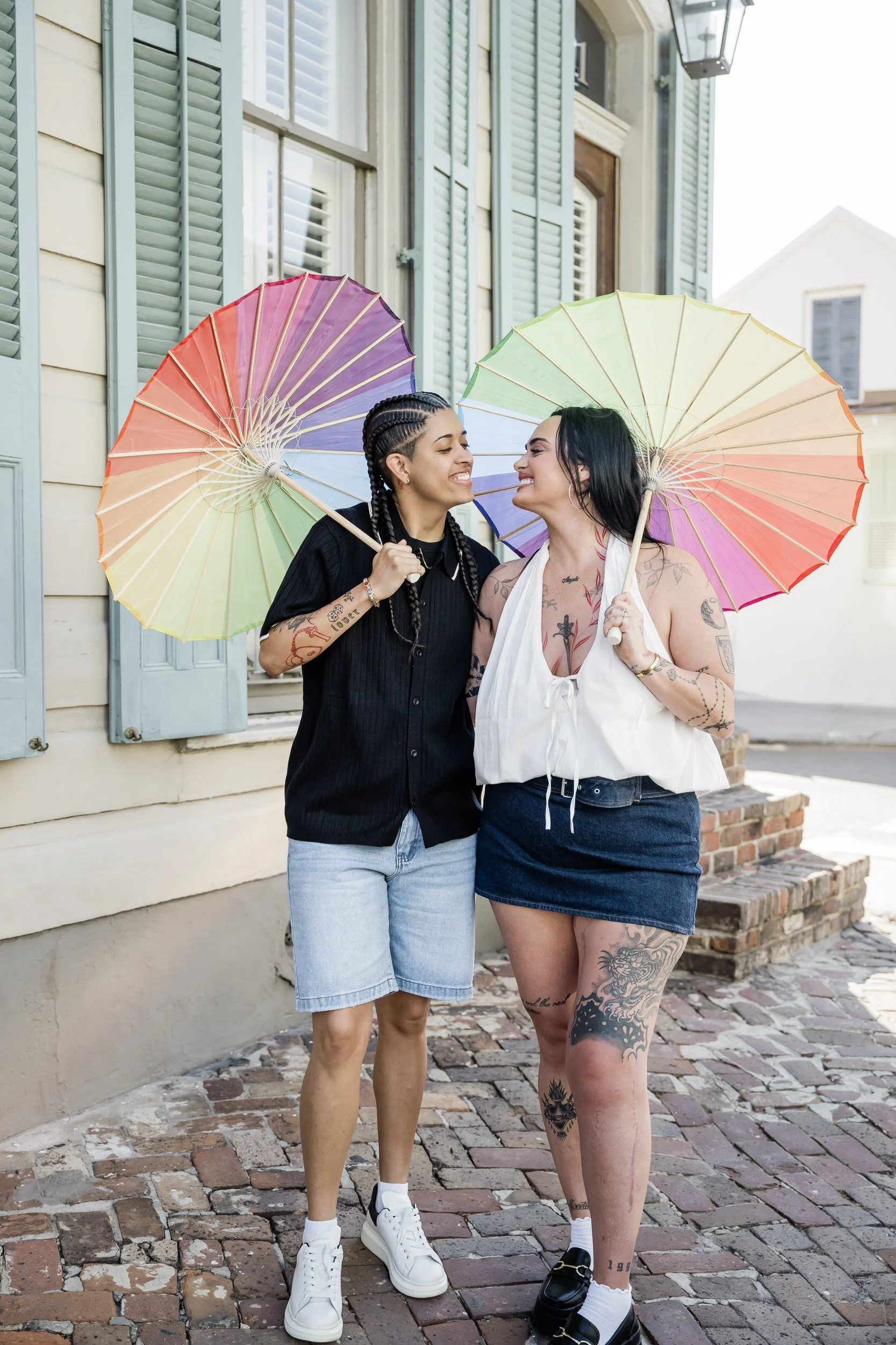 A couple walking together smiling as they hold rainbow umbrellas