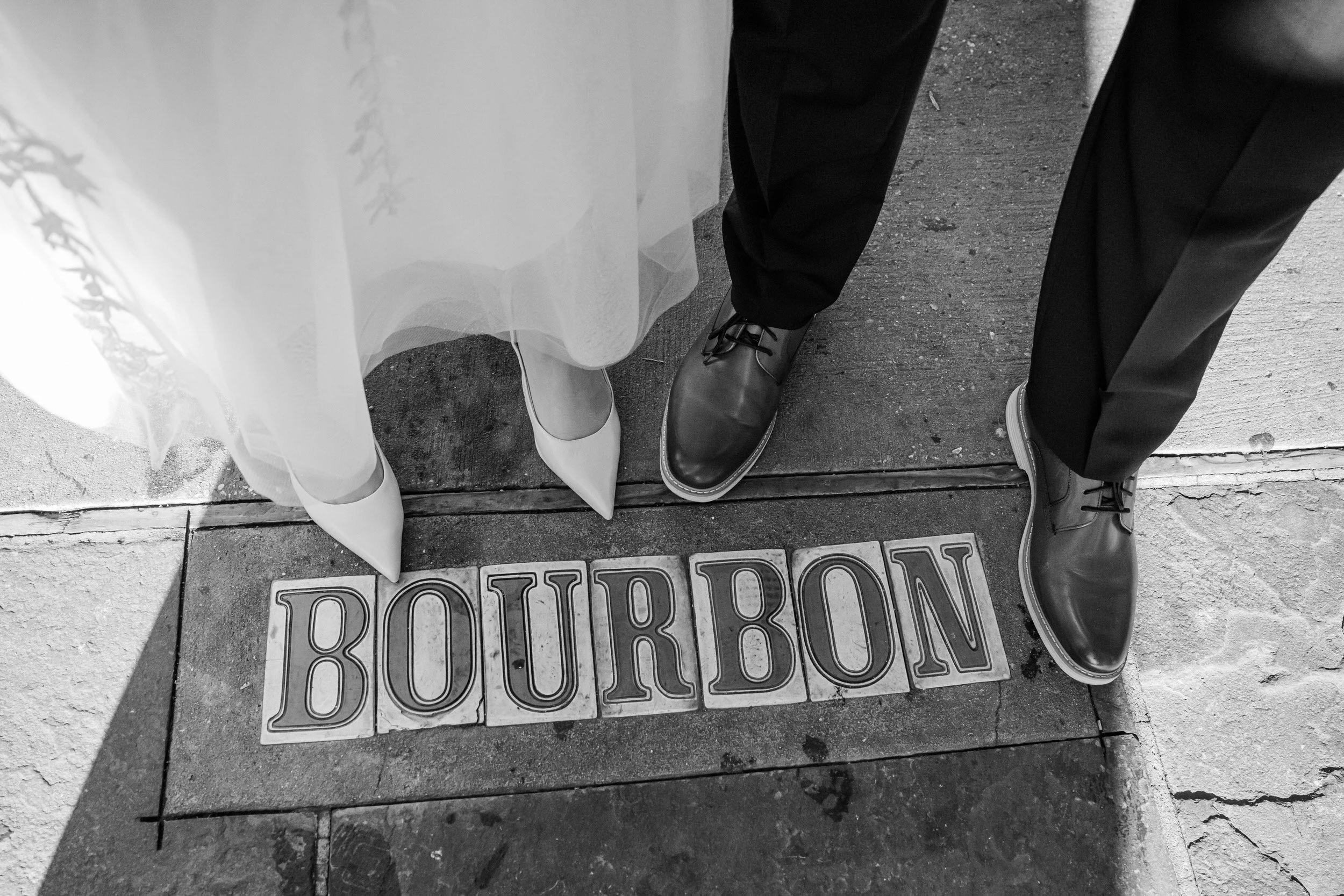 A close up of two people standing on a city sidewalk with the words "Bourbon" on the street below them