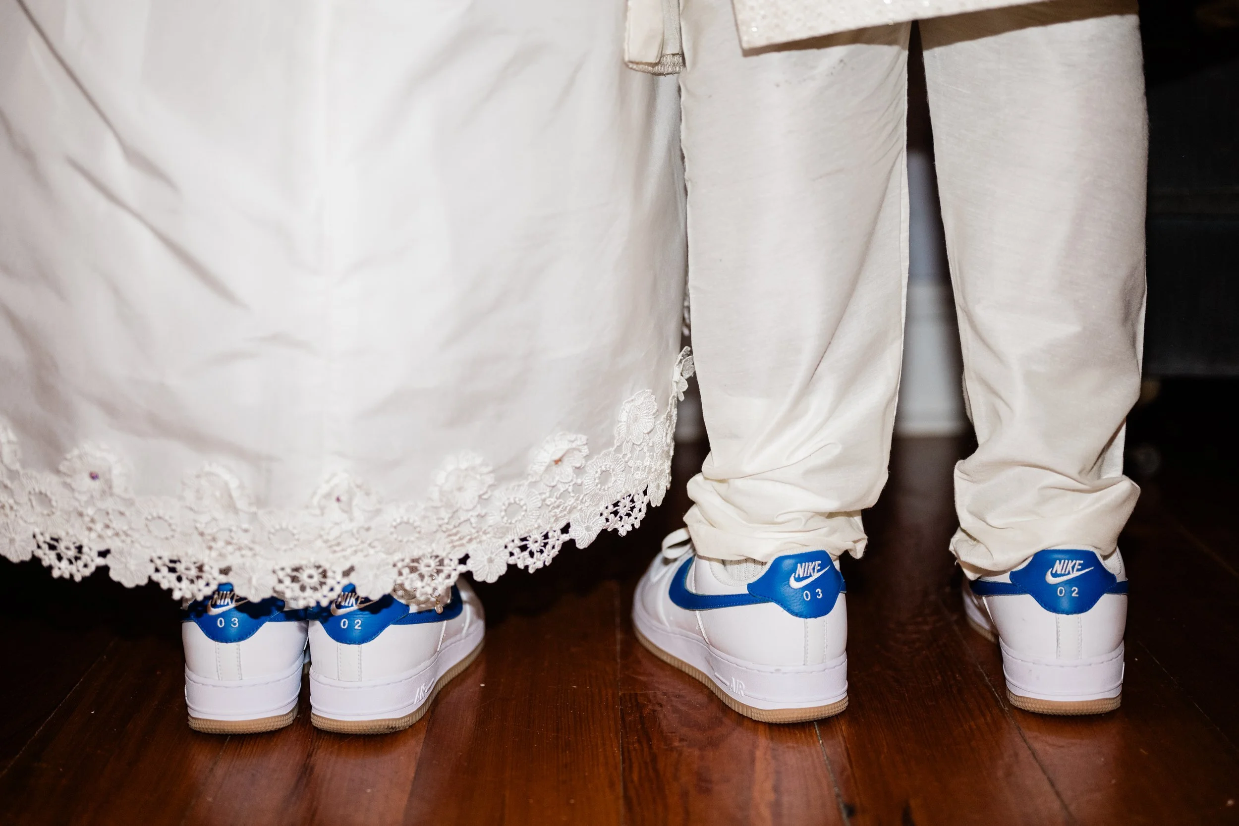 A close up of the backs of two newlywed's feet showing off matching Nikes