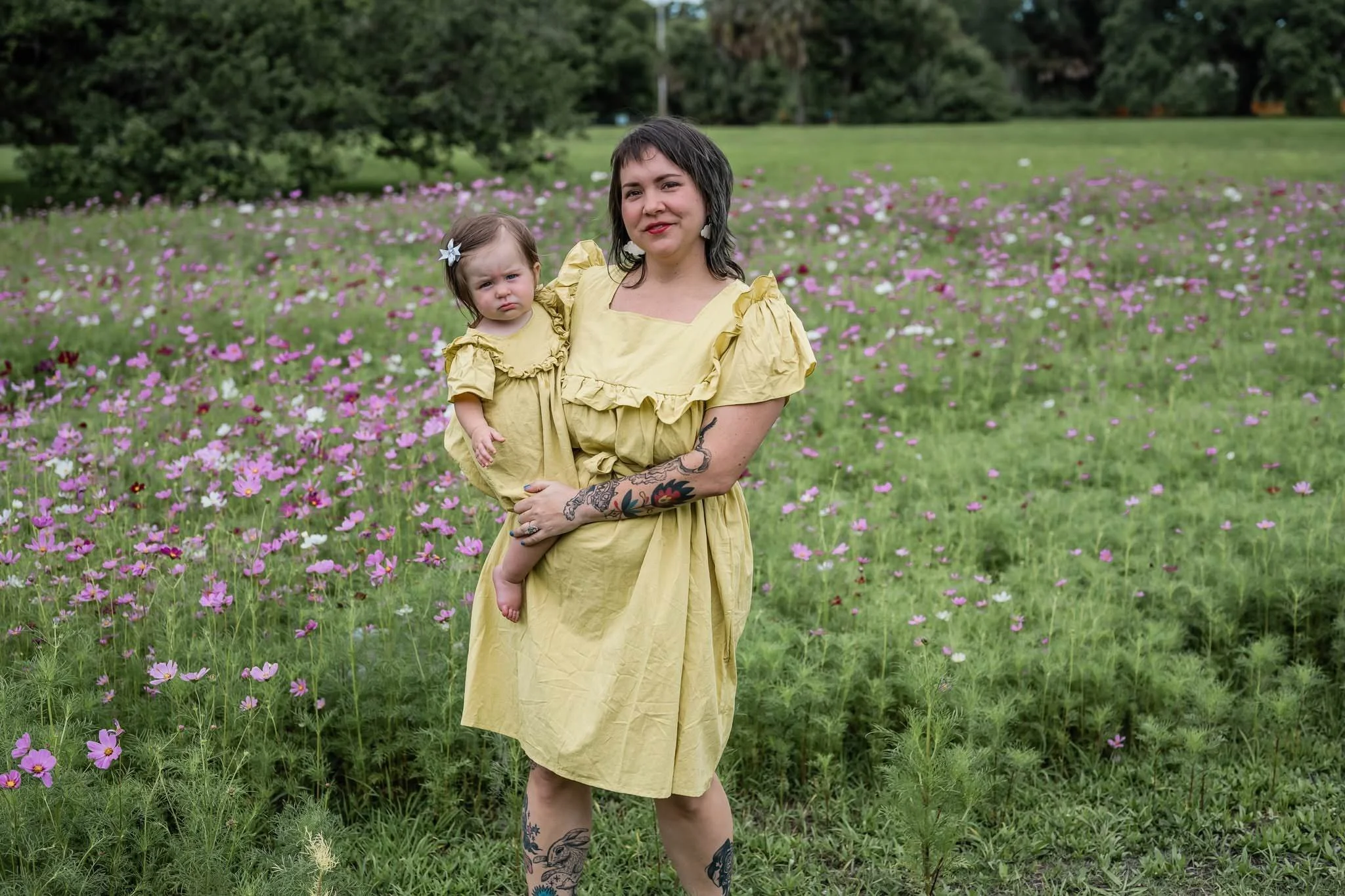 Ash standing in a field with her child on her hip