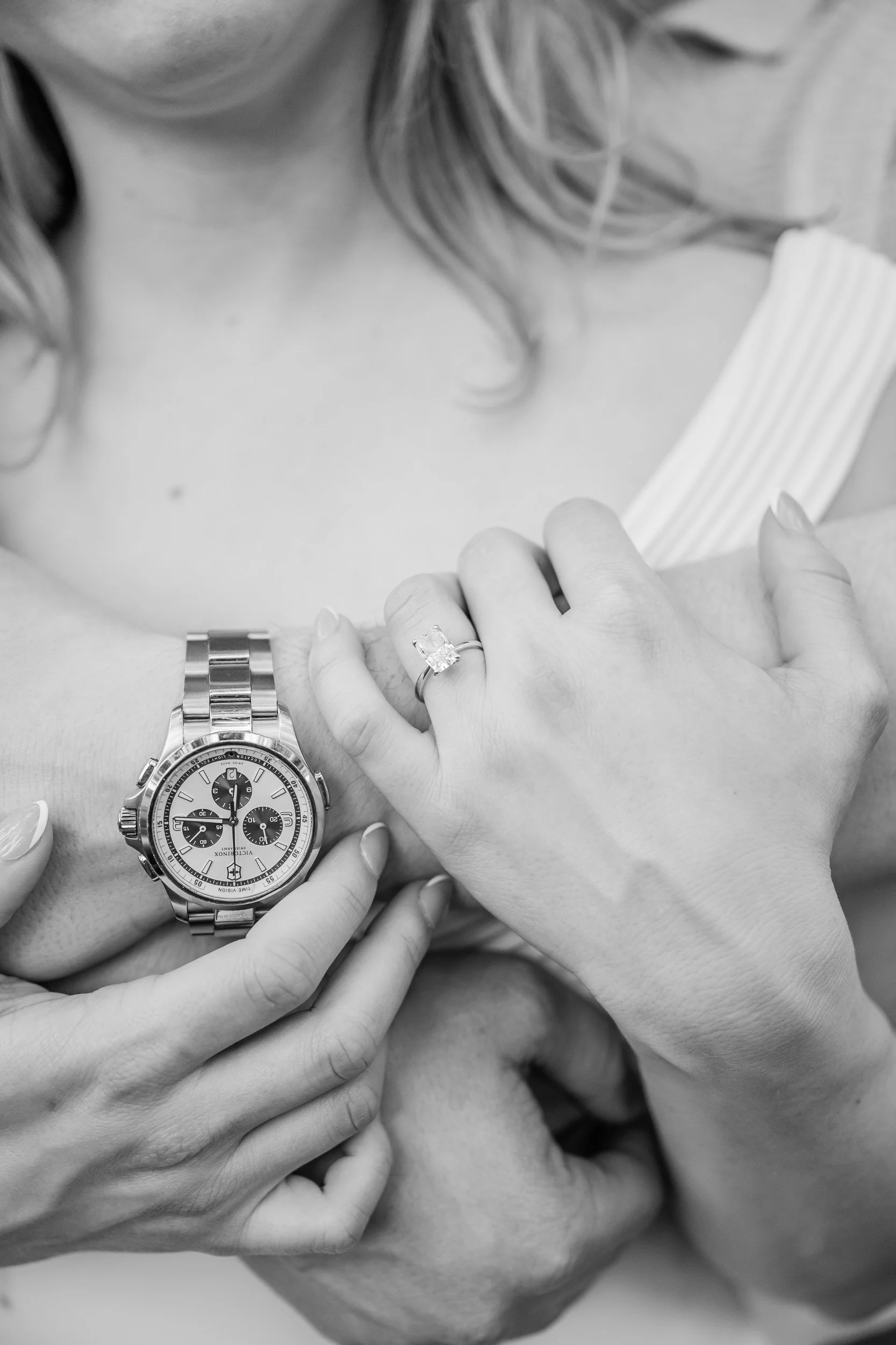 A close up of someone hugging their partner from behind showing off an engagement ring