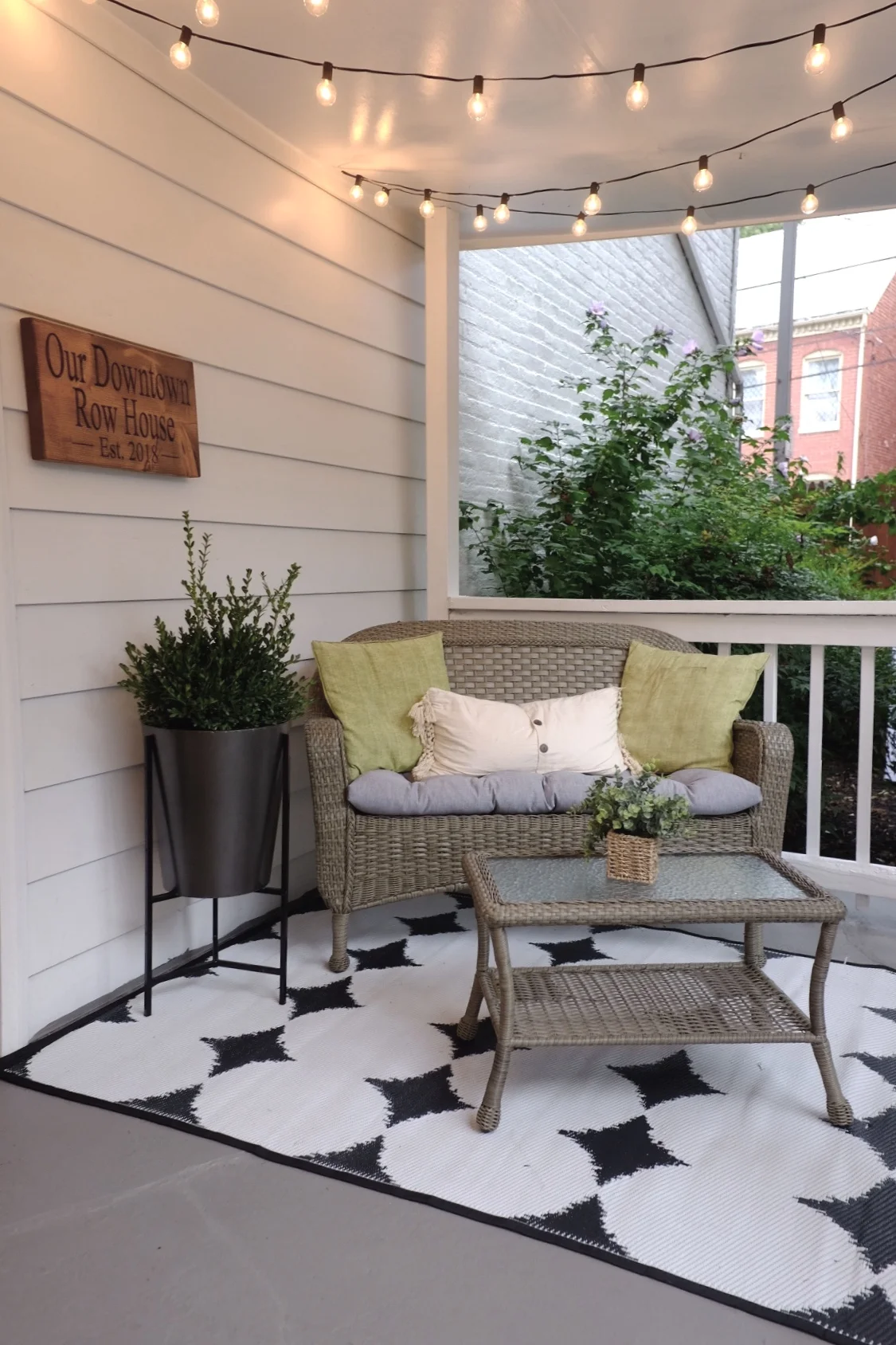 We added lights and a wicker couch so our guests can enjoy the backyard. Rowhouse sign is from Smith Crafted Wood Works .