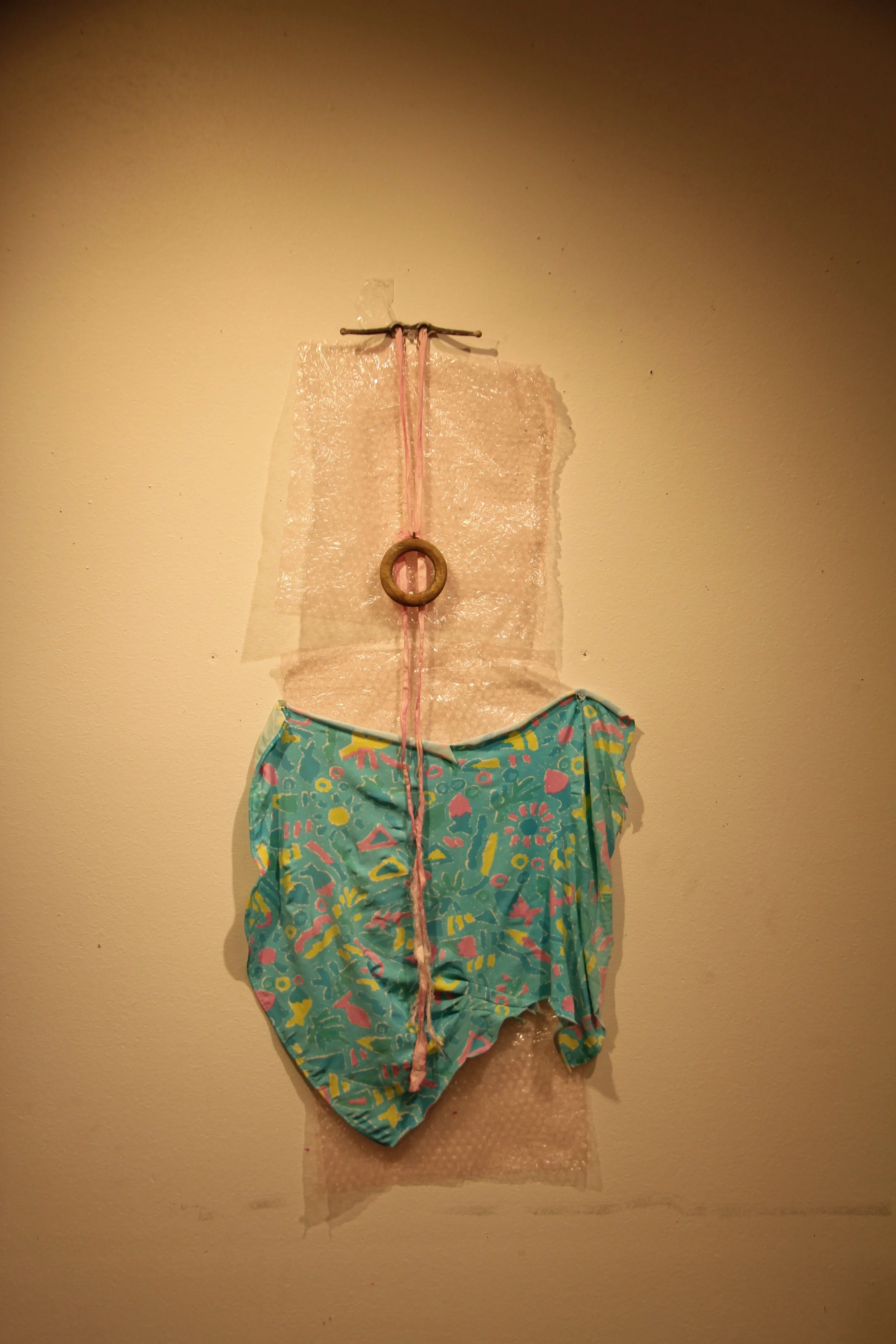 Mom, 2016. Plastic, cloth, wood, thread, tape. 19 x 31 inches.