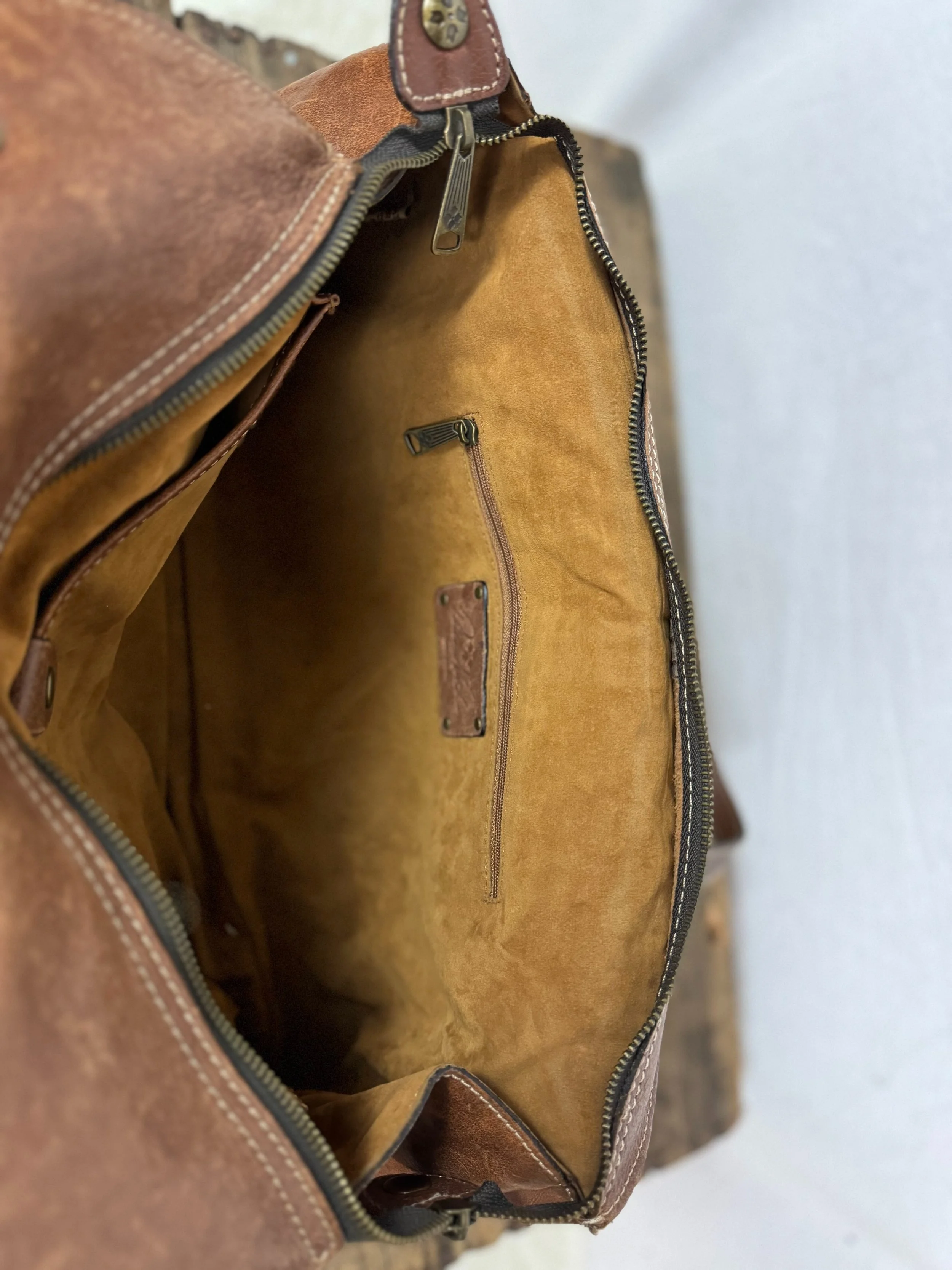 Inside view of Patricia Nash Ergo leather handbag with studs with inner zipper pocket and inner button pocket