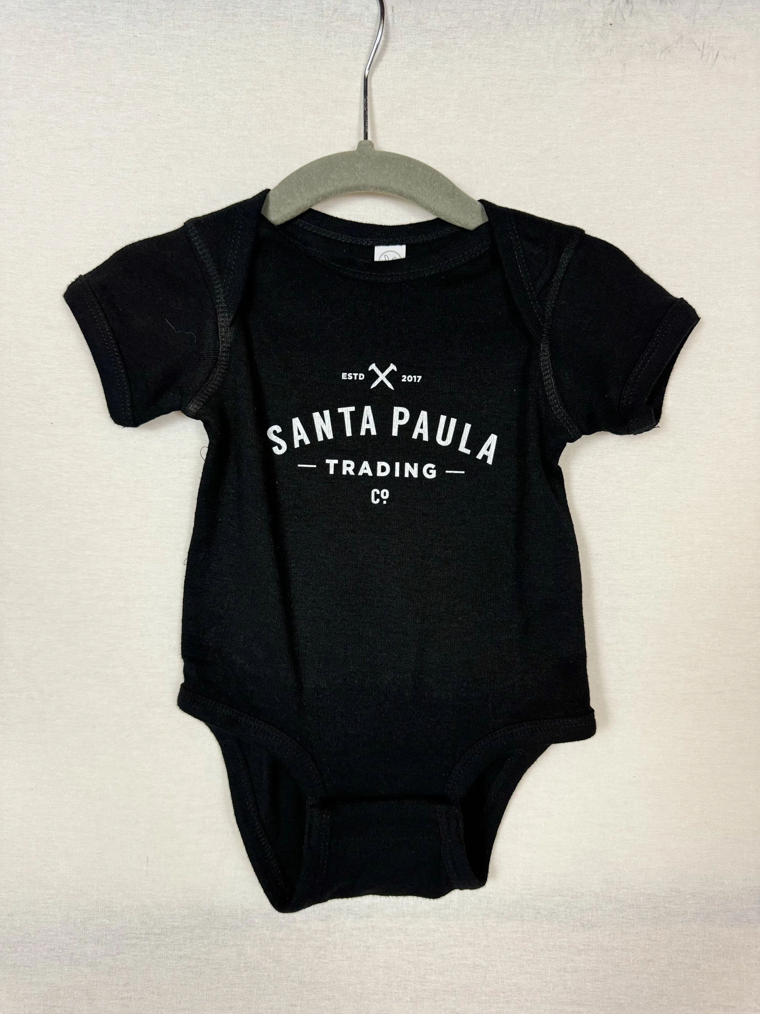 Santa Paula Trading Co Baby Onesie front view with logo across chest in Black