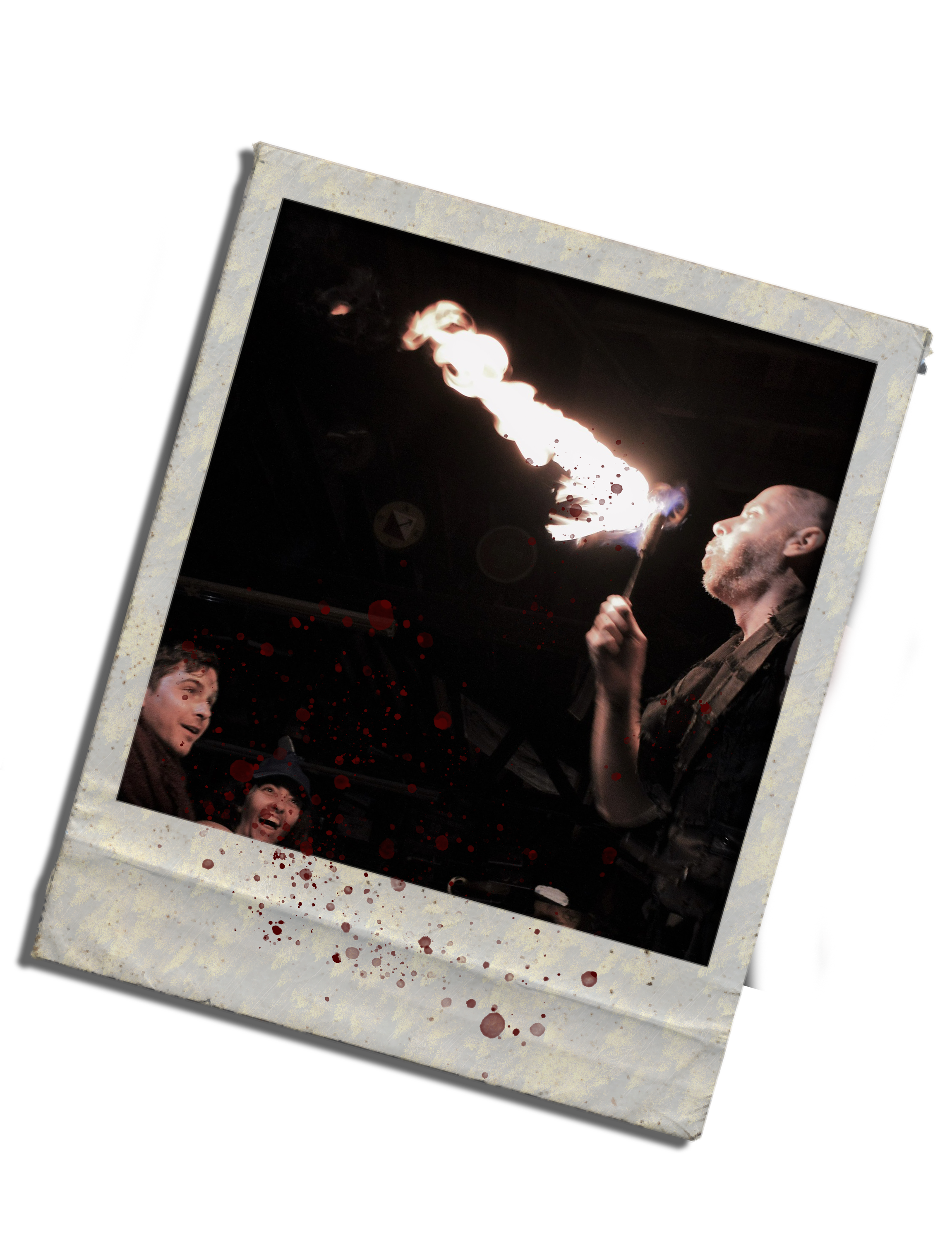 A person performing a fire breathing act with flames, surrounded by an audience watching in awe, in a dark setting with blood splatters on the border of the photo.