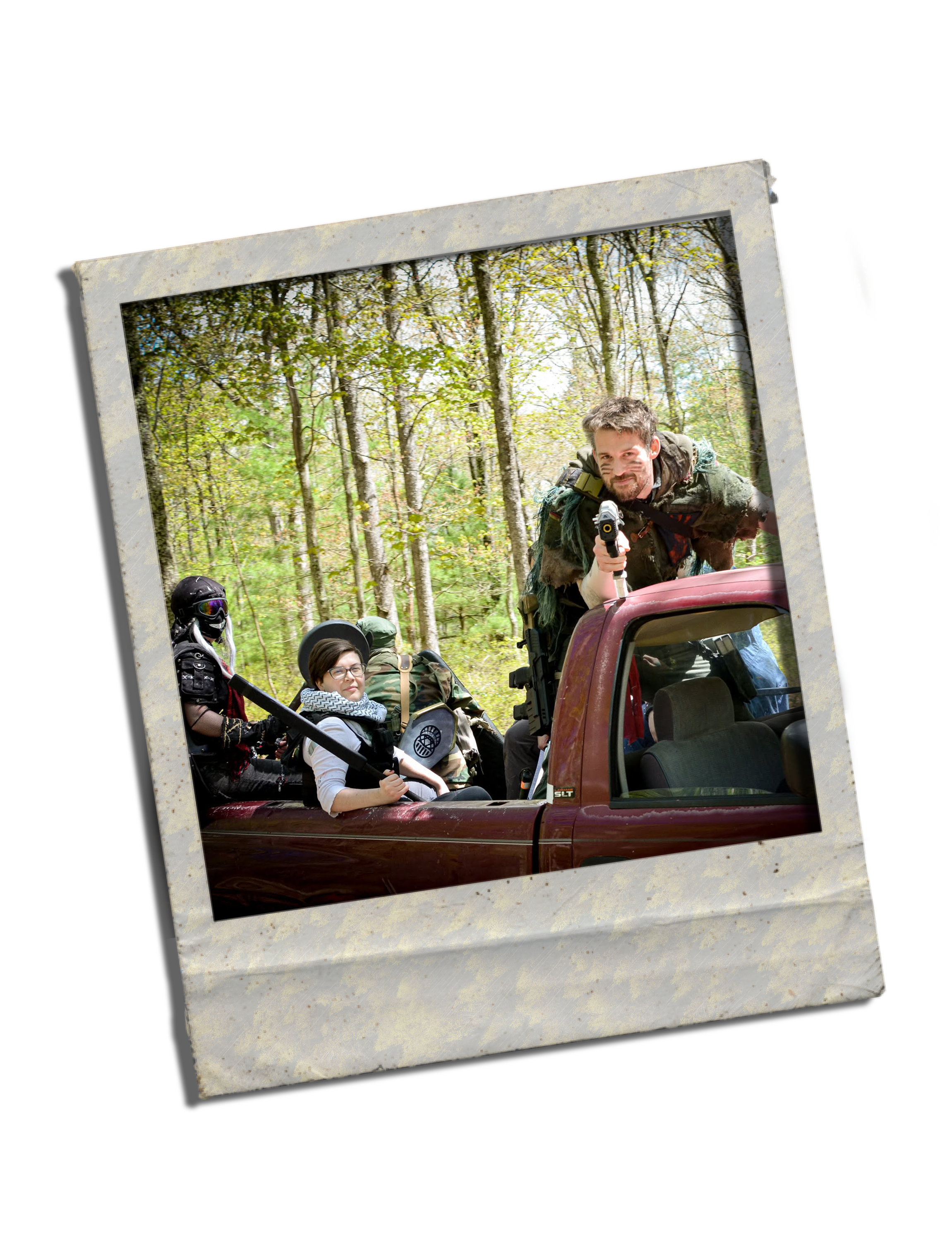 A group of people, including a man and a woman, in a pickup truck in a wooded area, with the man holding a gun and smiling at the camera.