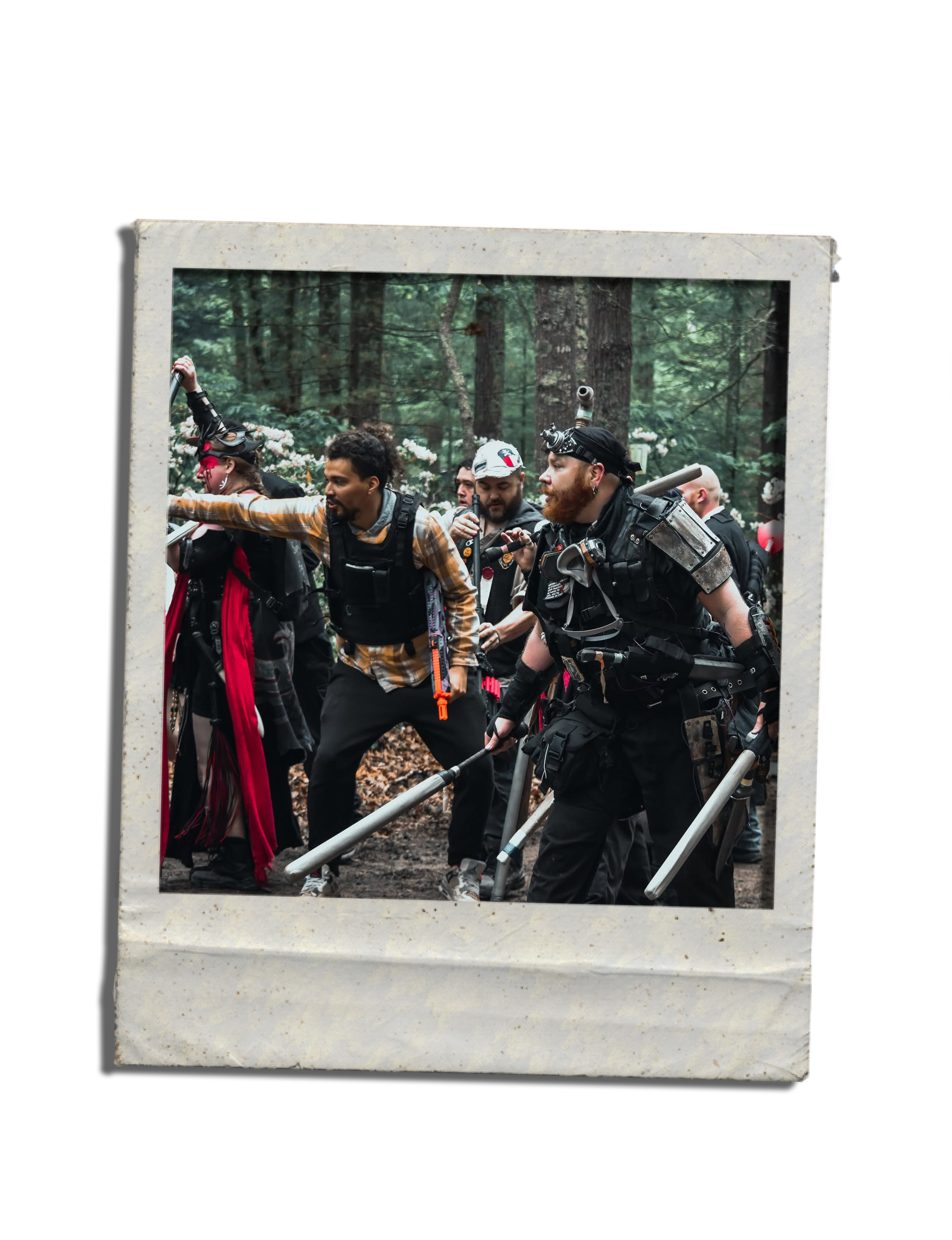 Group of people holding a large frame, dressed in black tactical gear, in a forest setting during daylight.