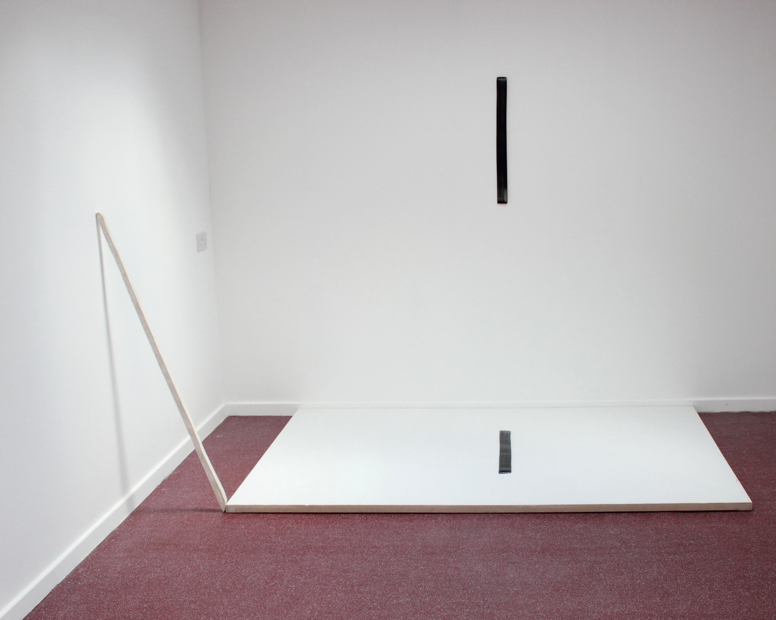  Photograph of an untitled painting installation, in which a brush mark cast in plaster, then painted with oil paint, hangs on the gallery wall, a second brush mark, mirroring the first is placed on top of a canvas on the floor. A third one, cast in 