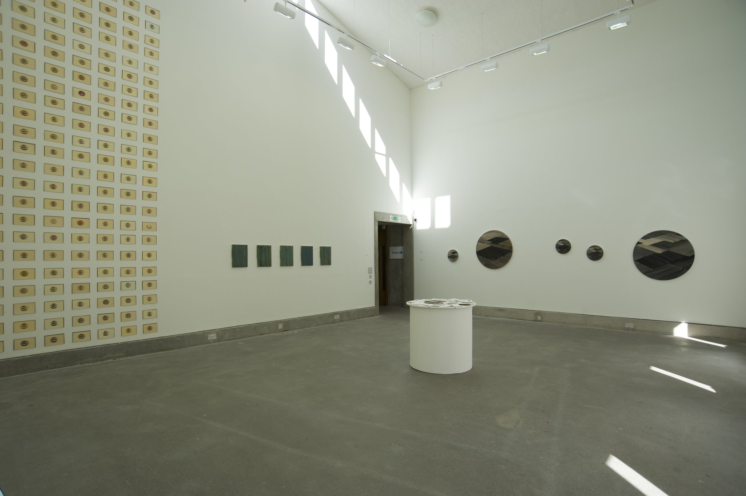  Image of the gallery showing James Quin’s  installation, Henry Tietzch-Tyler paintings, and on the far wall, M. B. O’Toole’s circular paintings. At the centre of the gallery floor a circular plinth displaying Christine Arnold’s book. 