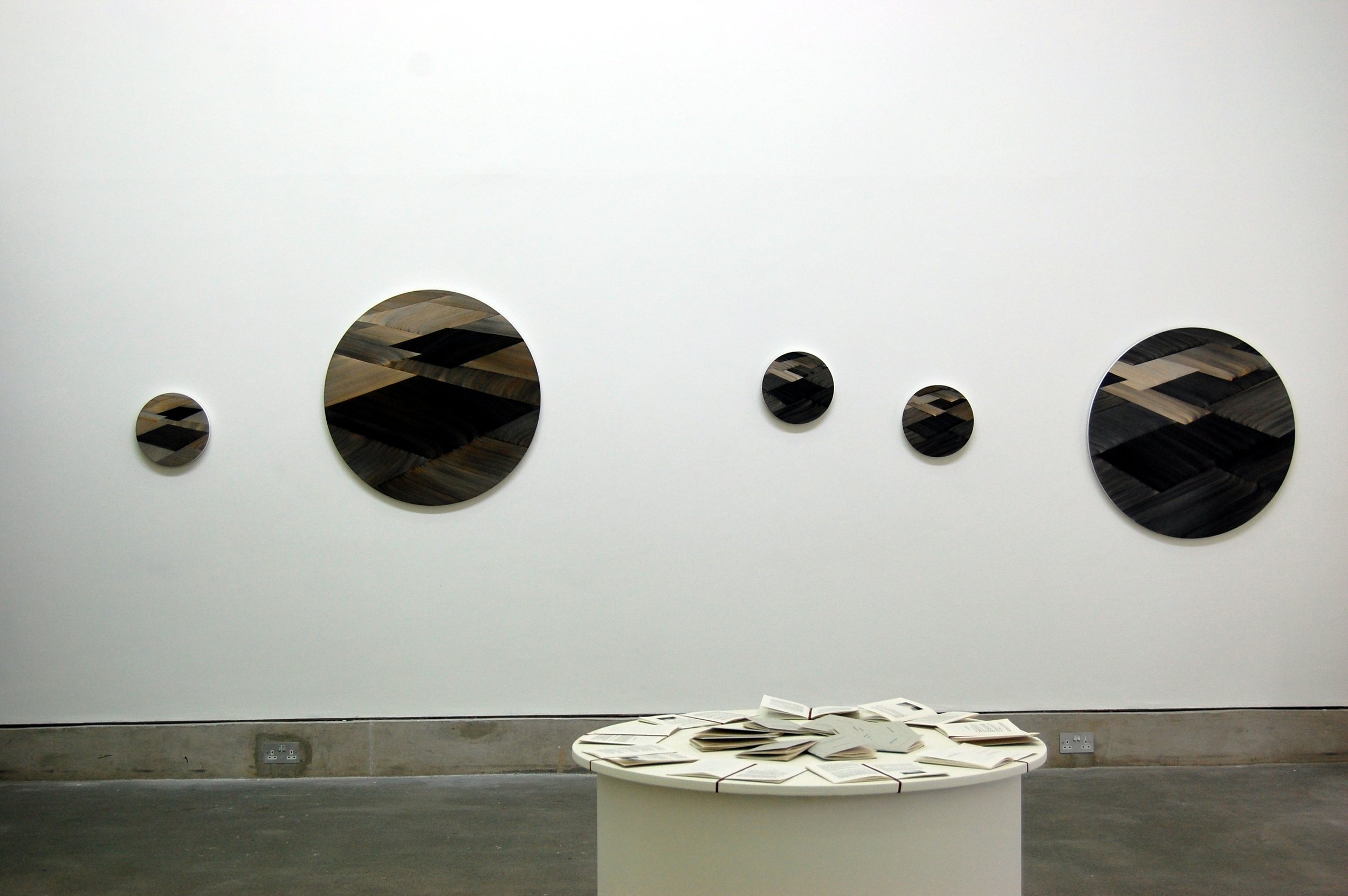  Image of M. B. O’Toole’s circular paintings on the gallery wall and in the foreground, Christine Arnold’s book,  Walking, Dreaming, Thinking: A Book of Reflections.   