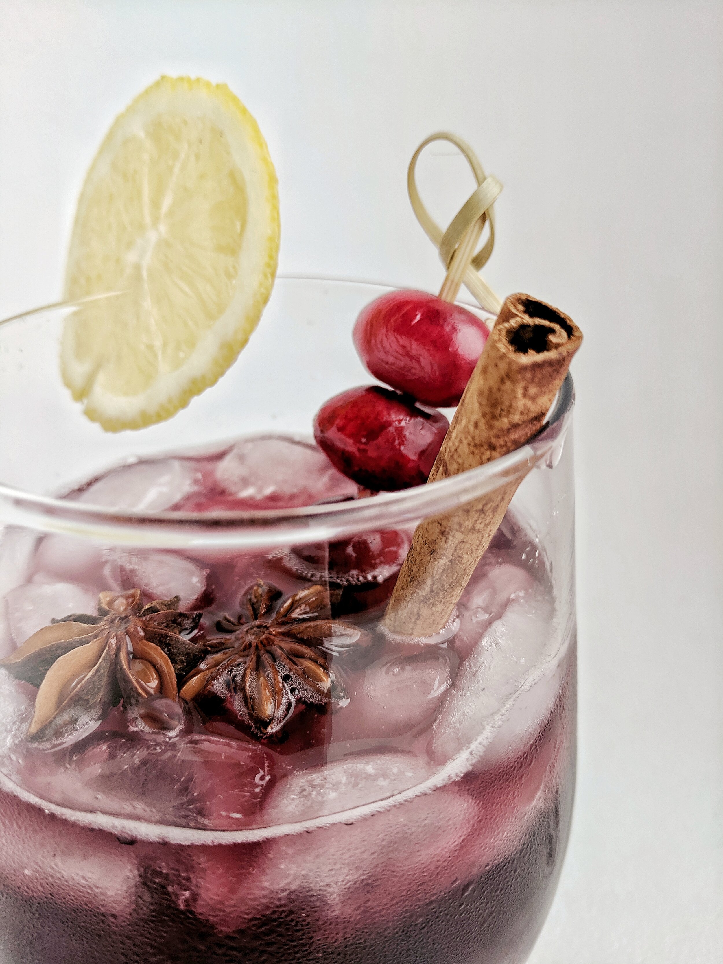 Cranberry sangria in glass with lemon cinnamon star anise garnish