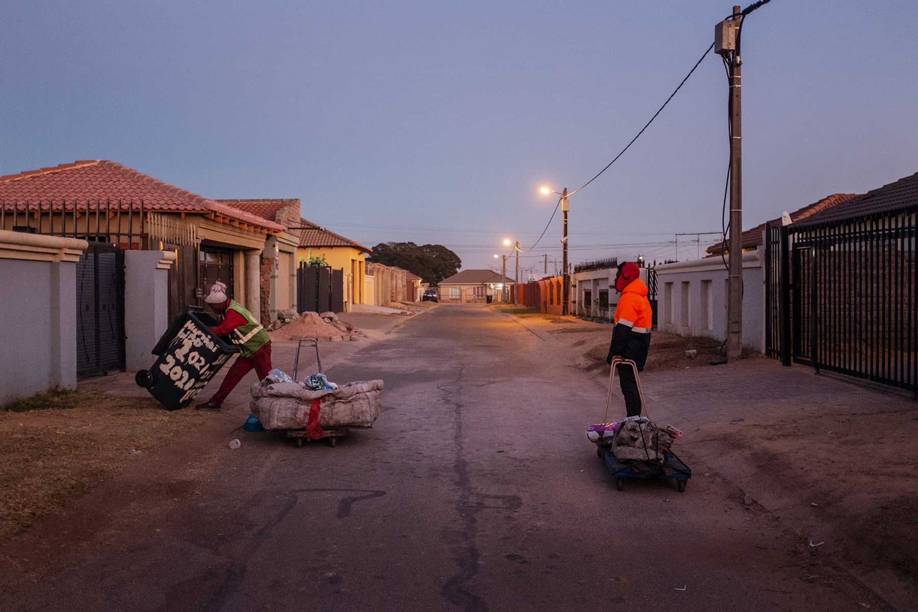 Scelo Sithole, 38, speaks with Tumelo Ikaneng, 21, while they collect waste from trash bins in the streets of Johannebsurg, South Africa in the early morning of June 12, 2019.