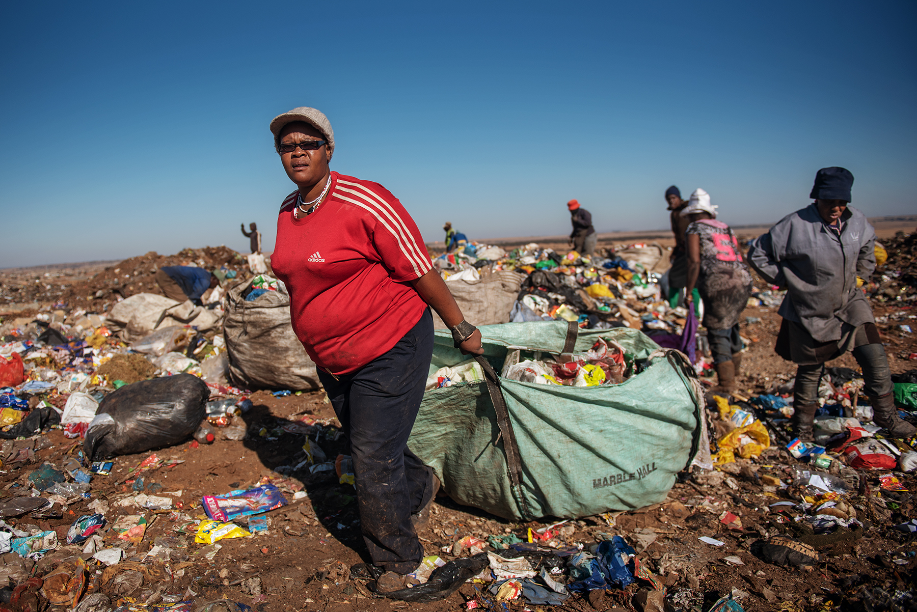 Eva Mokoena (L), a 33 years old South African informal waste picker, drags a sack filled up of waste dumped by a garbage truck at the Palm Springs landfill in the outskirt of Johannesburg, South Africa, on June 28, 2019.