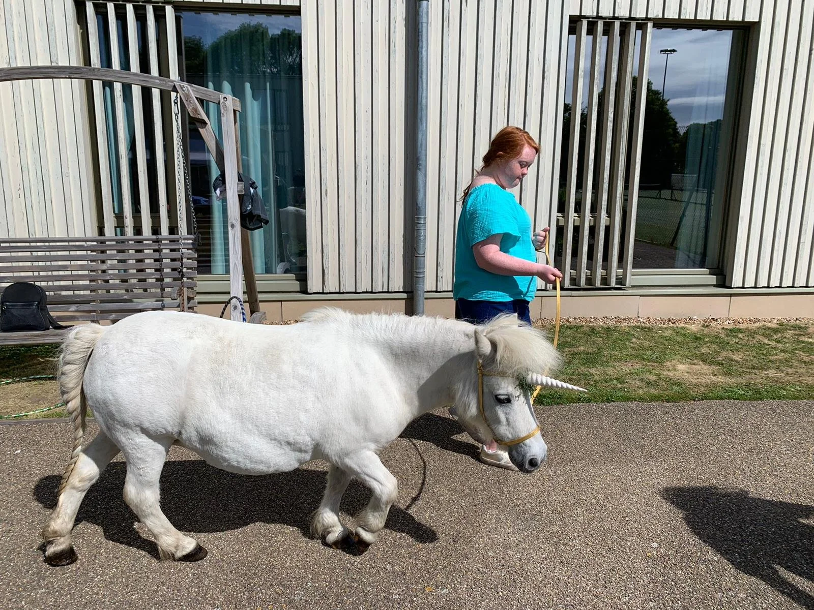 a holiday-maker walking alongside a shetland pony dressed as a unicorn