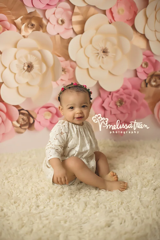 she had smiles for days during her first birthday photo shoot and cake smash, stlyed with pink and cream rosettes