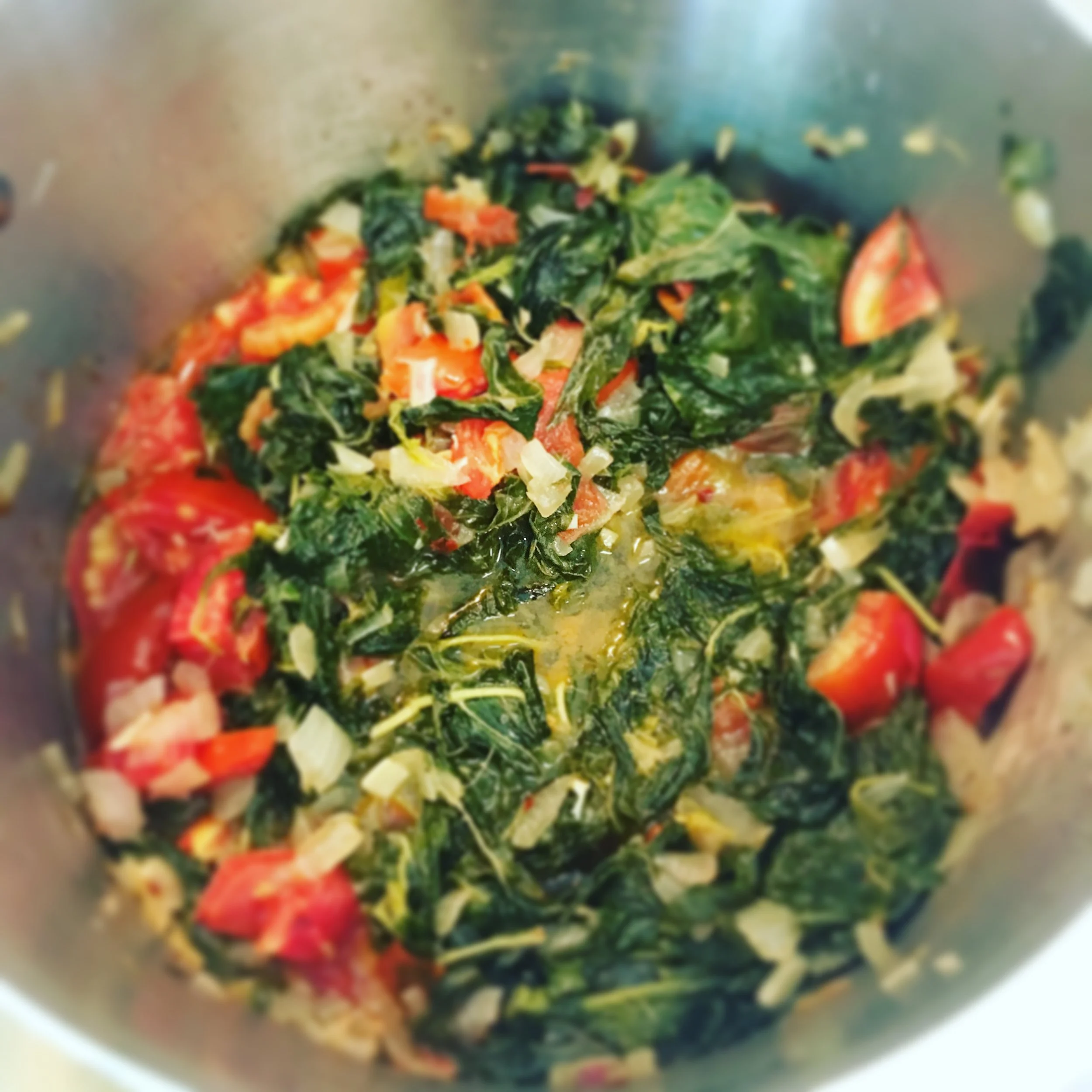 Spinach is cooked with onions, garlic, tomatoes, red pepper flakes, salt and pepper.