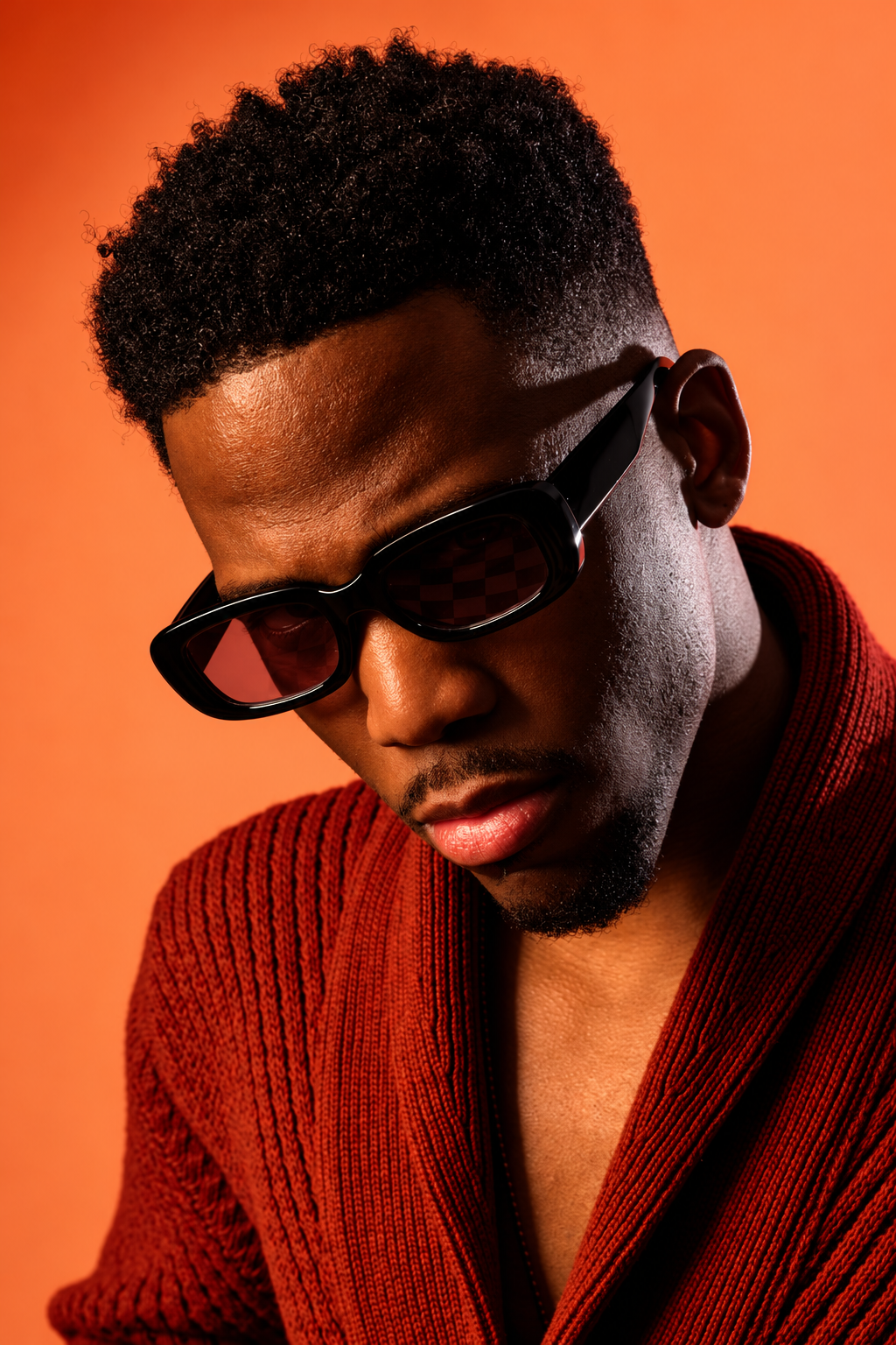 Portrait éditorial chaleureux en lunettes noires.png