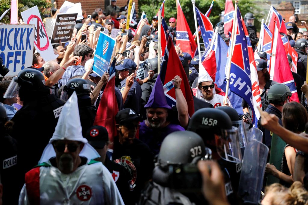 Racists get out their finest sheets and Confederate flags for white supremacy rally amongst a small gathering of police officers. (google.com)