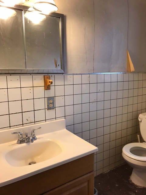 Before: Bathroom with old tile and chipping floor.