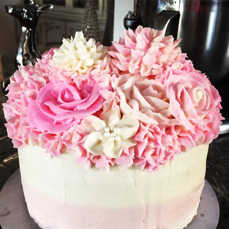 Pictured: blush ombre vanilla buttermilk cake with organic strawberry filling, topped with fresh-whipped vanilla almond buttercream flowers.