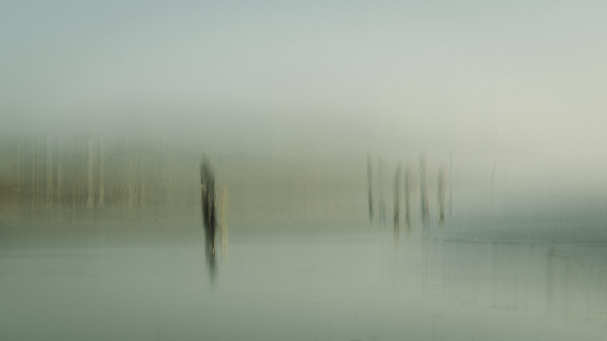 Impressionist ICM landscape photograph with ghosted figures in misty blue-green atmosphere, intentional camera movement capturing stillness and human interaction