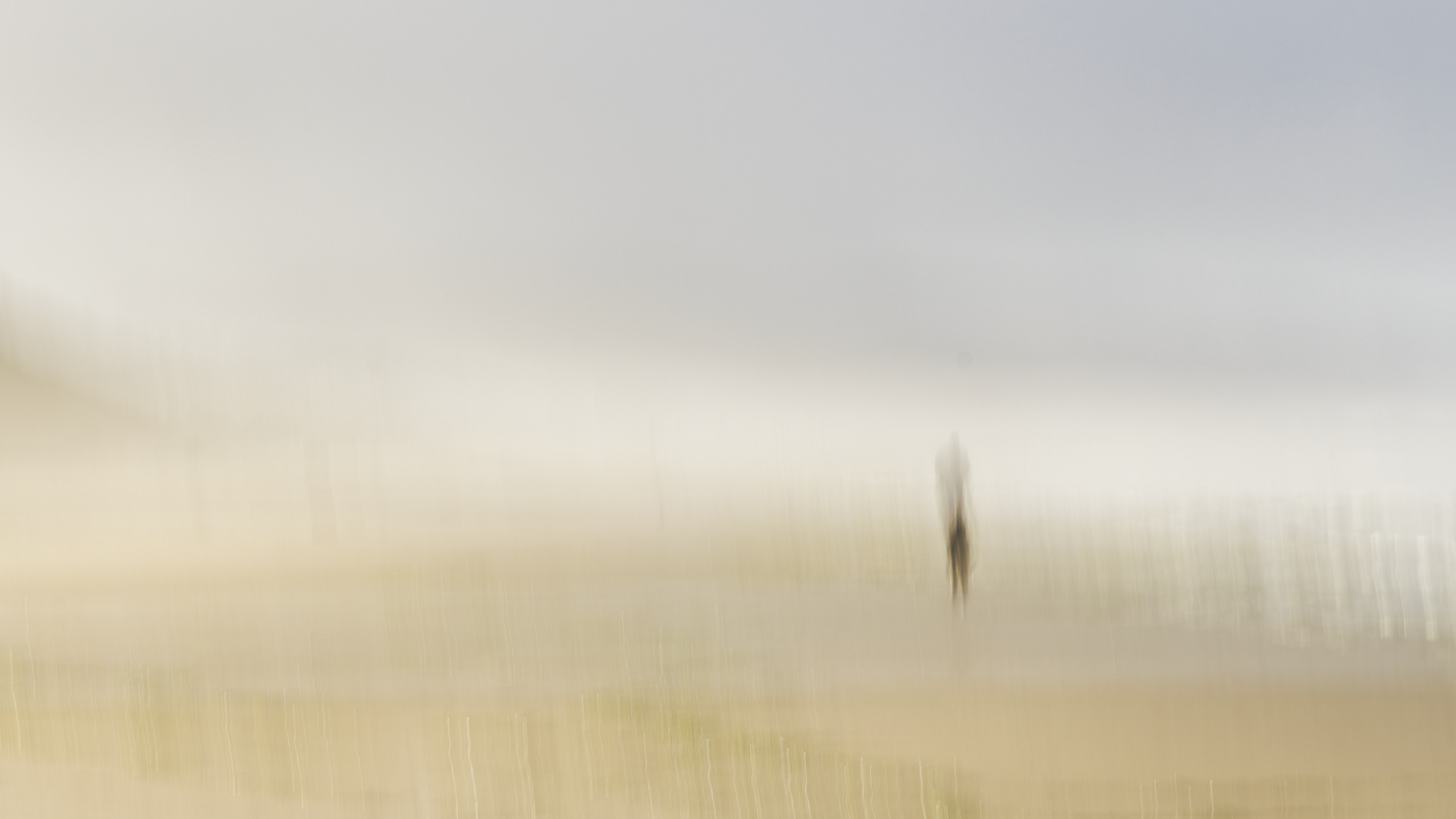 Minimalist impressionist ICM photograph with solitary ghosted figure in misty beige landscape, intentional camera movement exploring isolation and memory