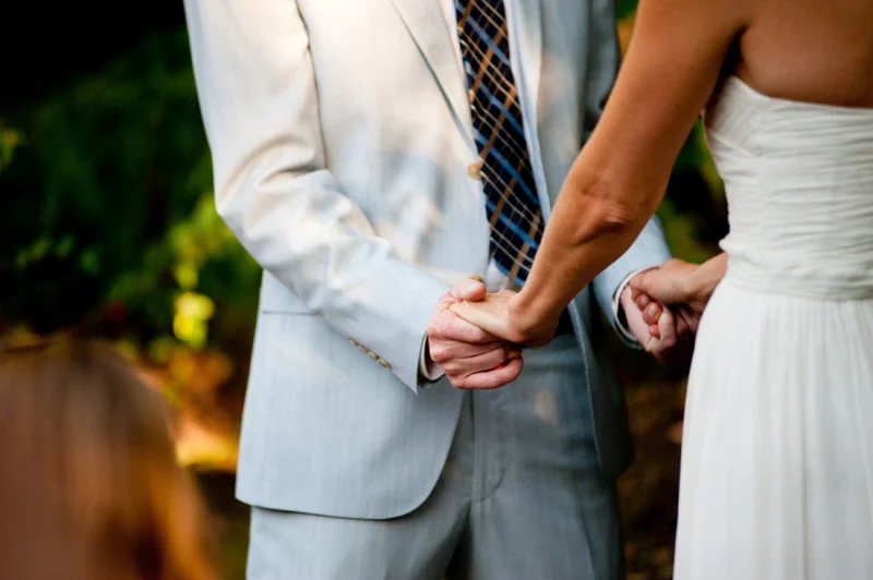 Detail of bride and groom holding hands during wedding ceremony in Oakland, CA