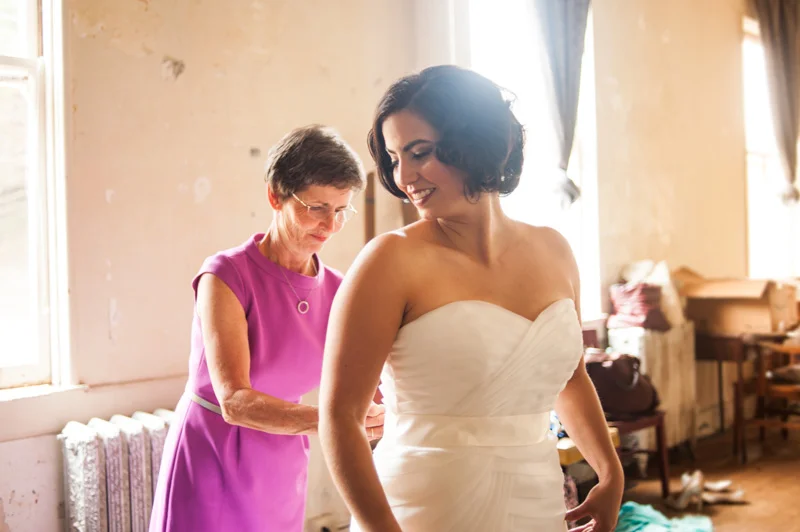 Mother helping bride into wedding dress
