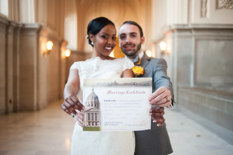 Bride and Groom holding marriage certificate in San Francisco at City Hall