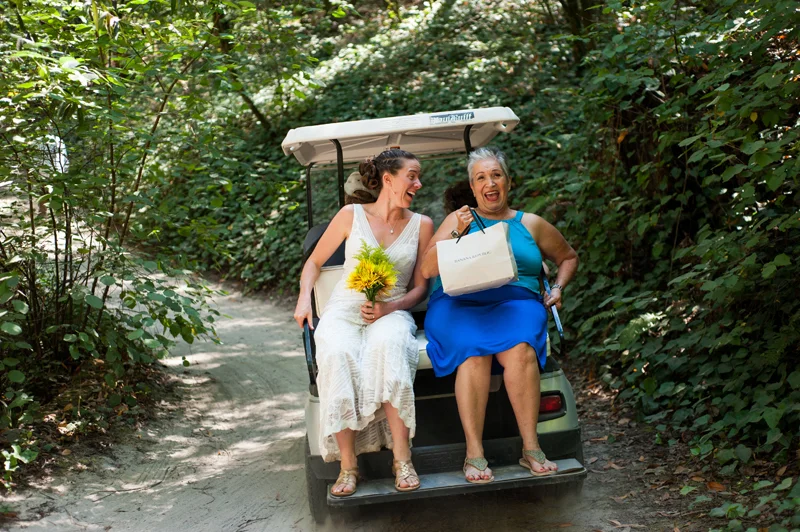 Bride and mother in law riding in golf cart on wedding day