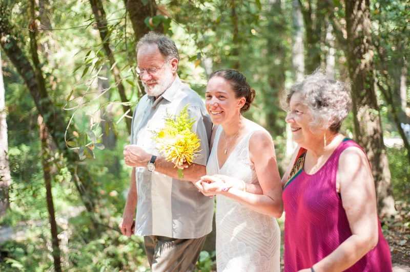 Bride walking down aisle with father and mother
