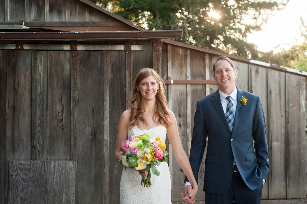 Bride and groom in front of rustic wood barn