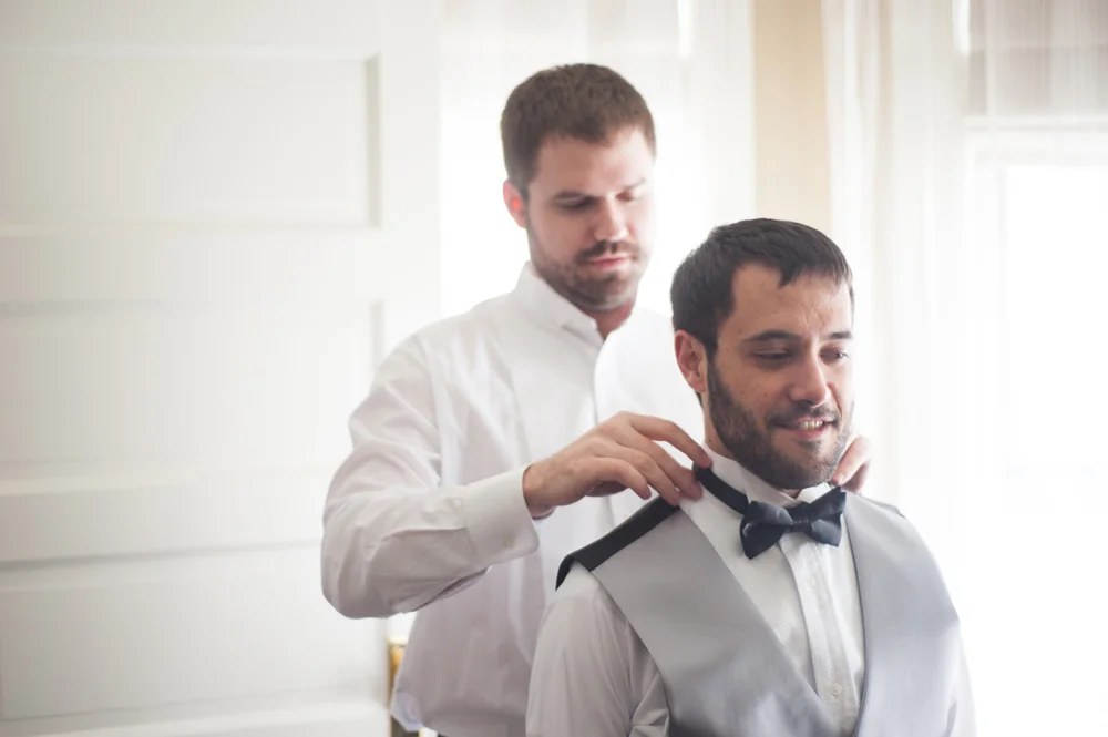 Best man helping groom with bow tie